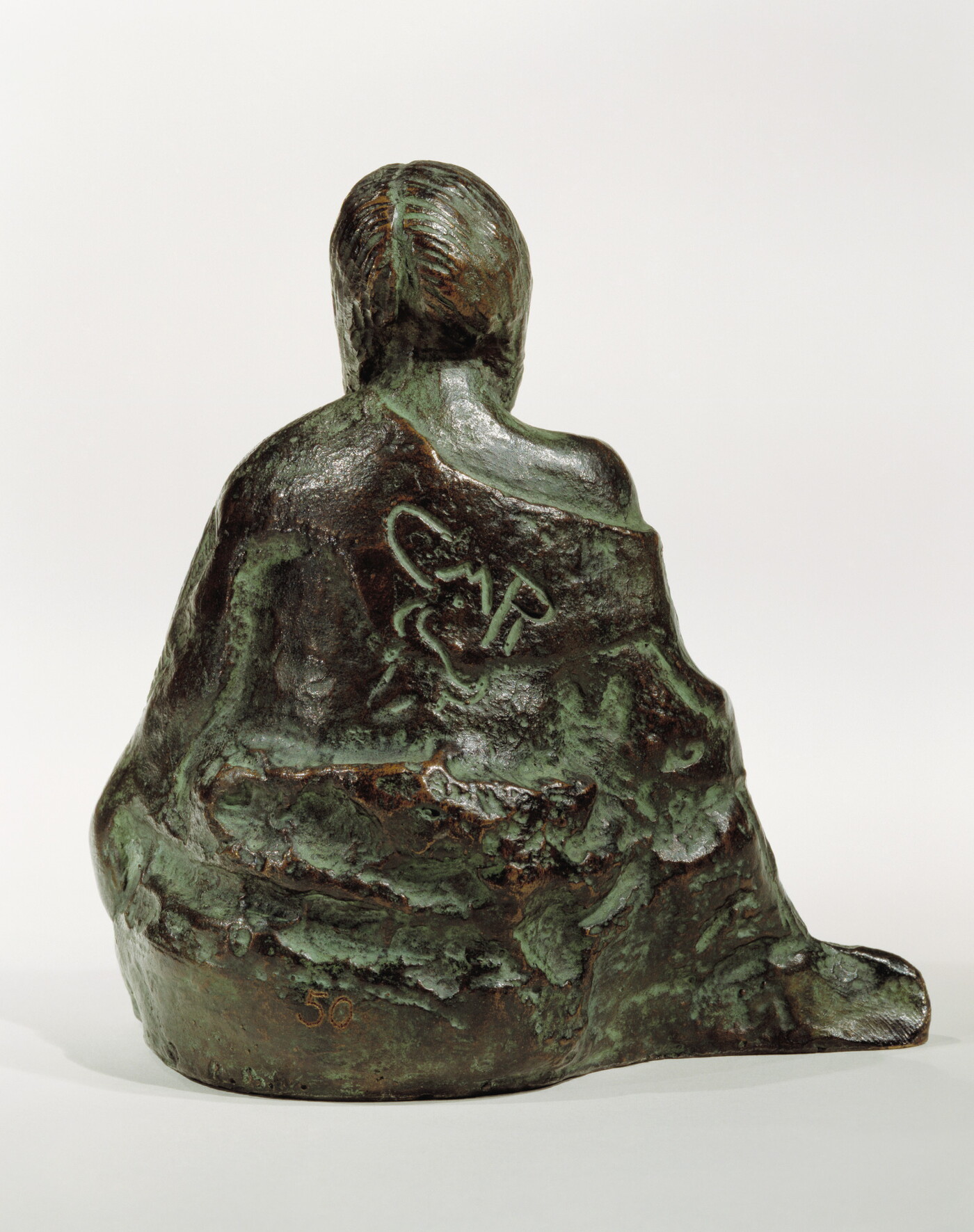A bronze sculpture of a seated Native American person wrapped in a robe.