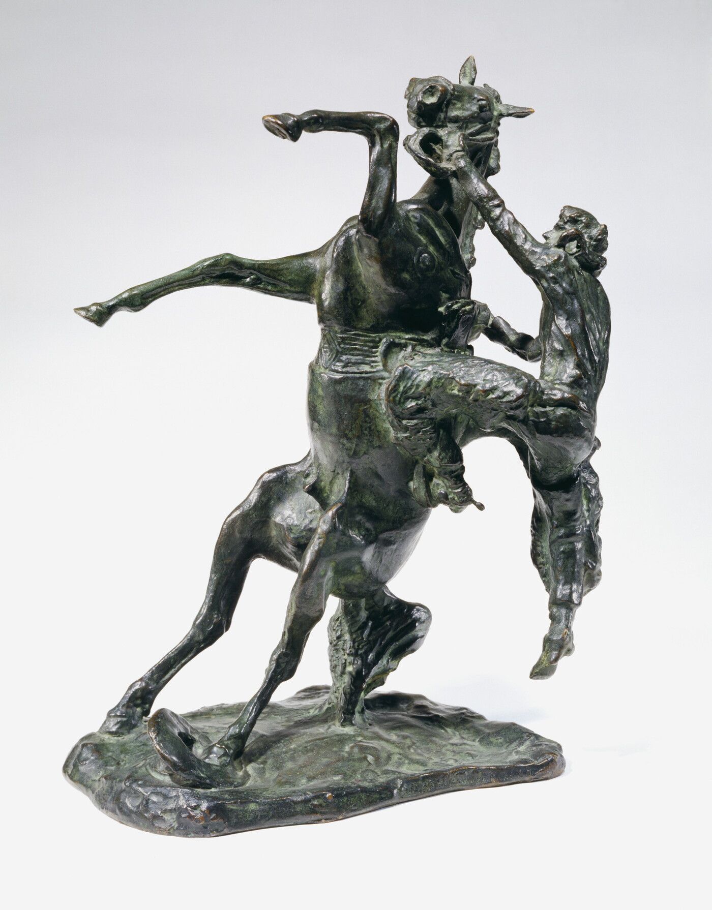 A bronze sculpture of a cowboy falling off the back of a rearing horse.