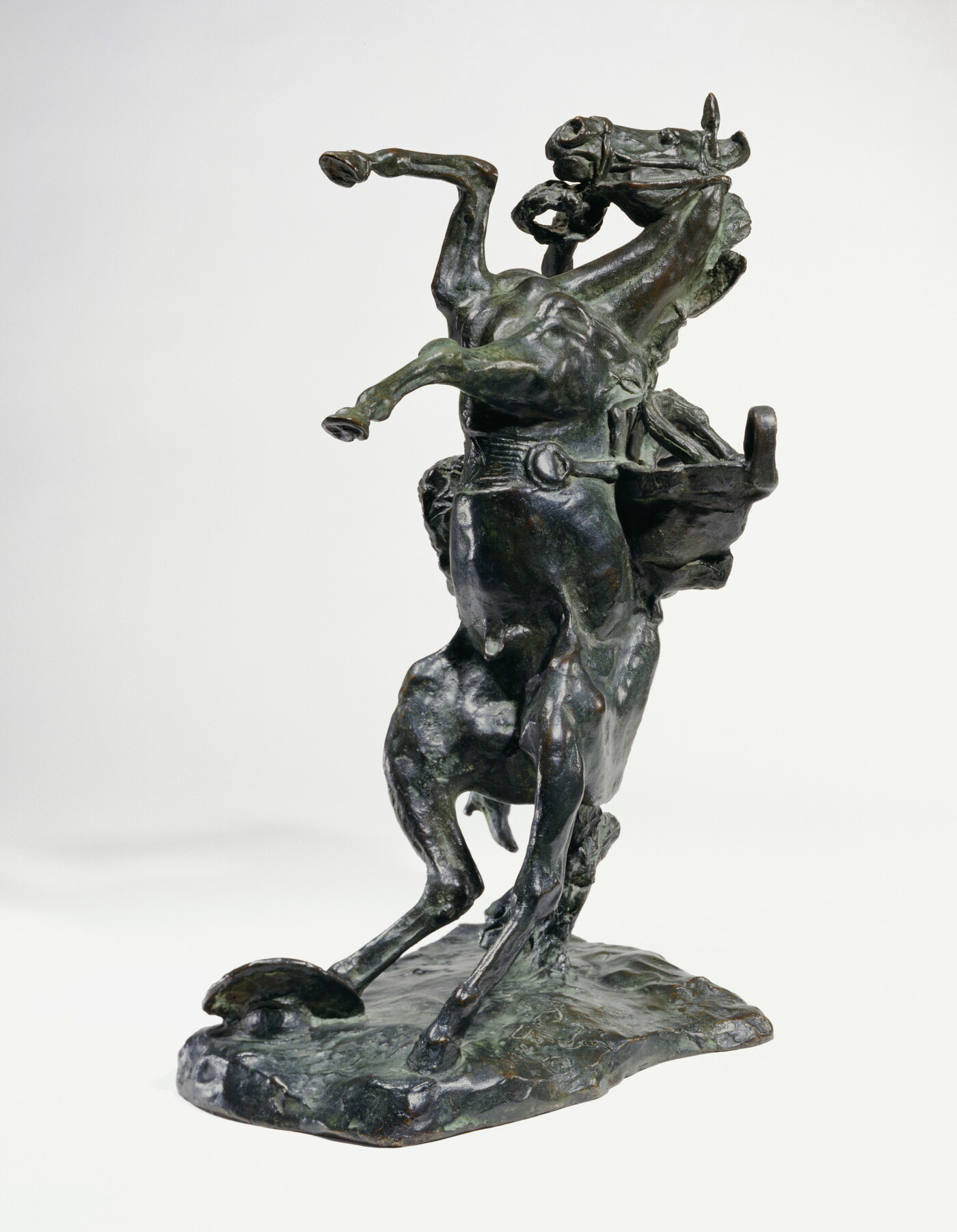 A bronze sculpture of a cowboy falling off the back of a rearing horse.
