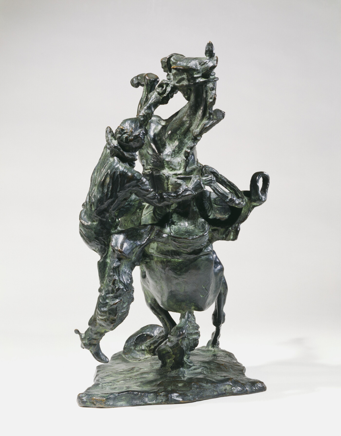 A bronze sculpture of a cowboy falling off the back of a rearing horse.