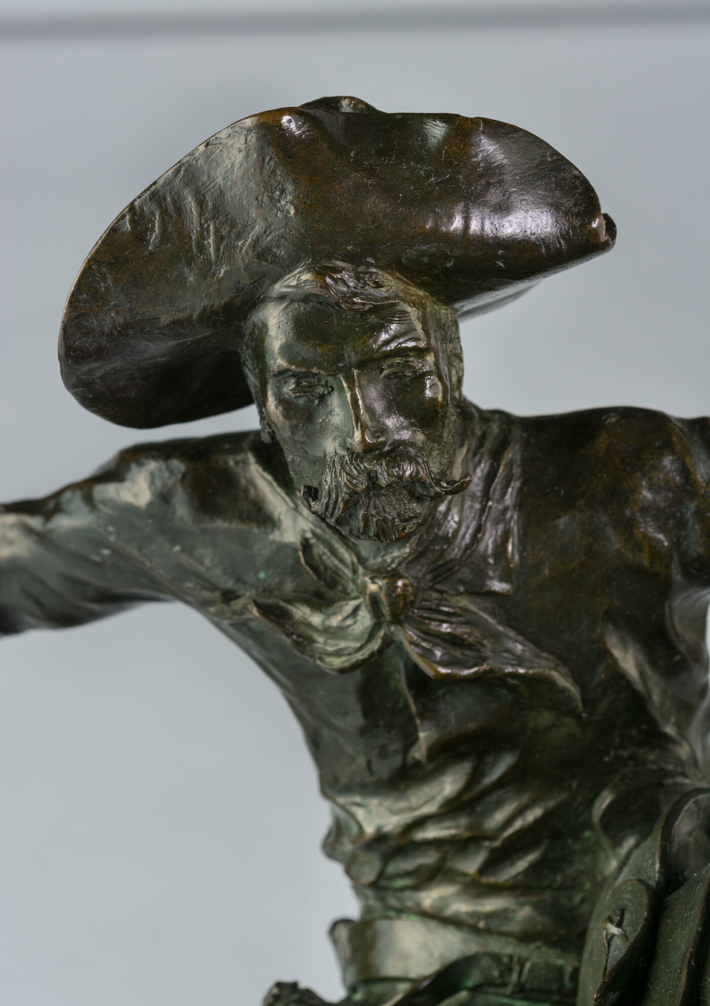 A detail of bronze sculpture of a cowboy balancing on a rearing horse.