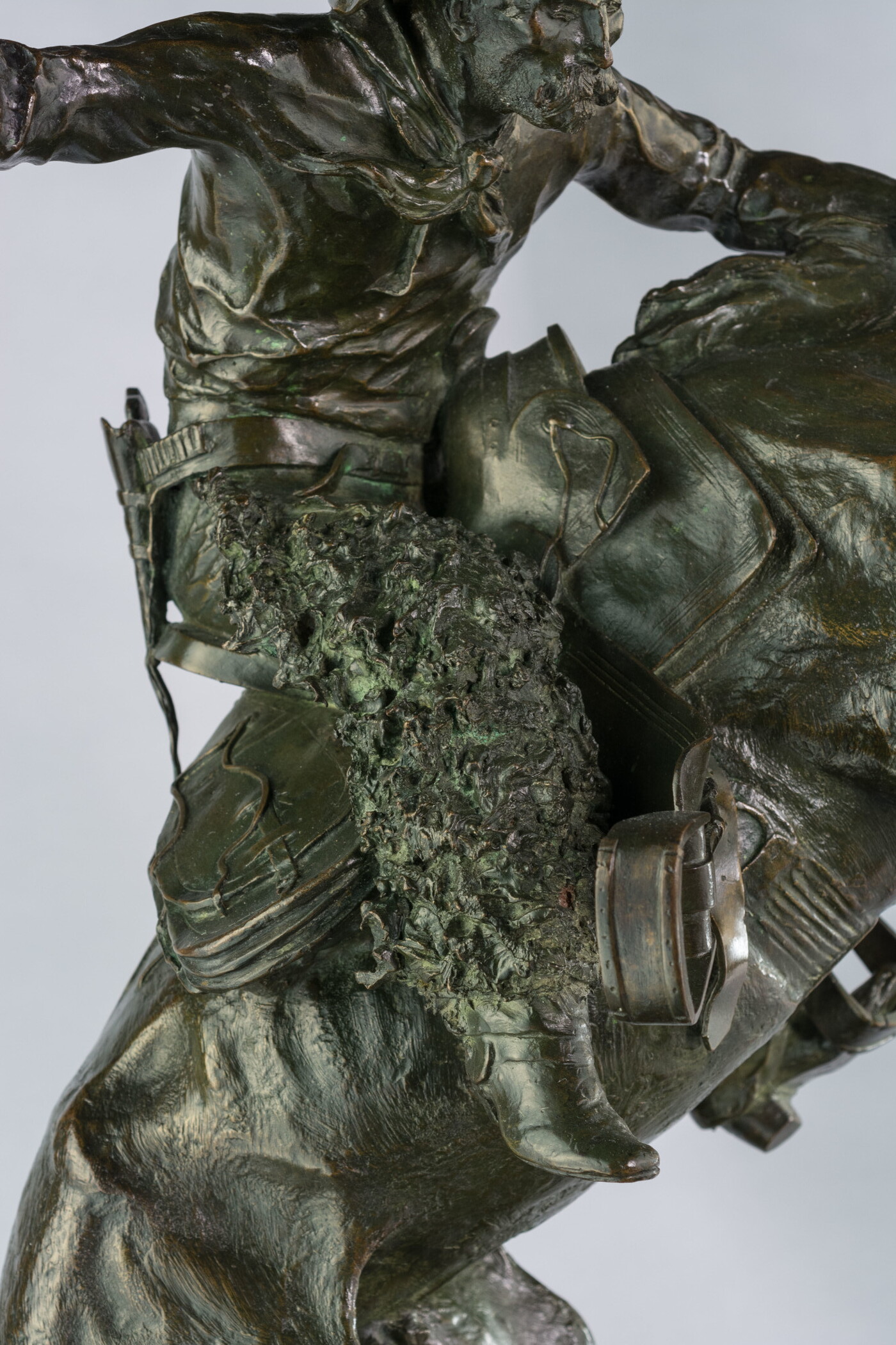 A detail of bronze sculpture of a cowboy balancing on a rearing horse.