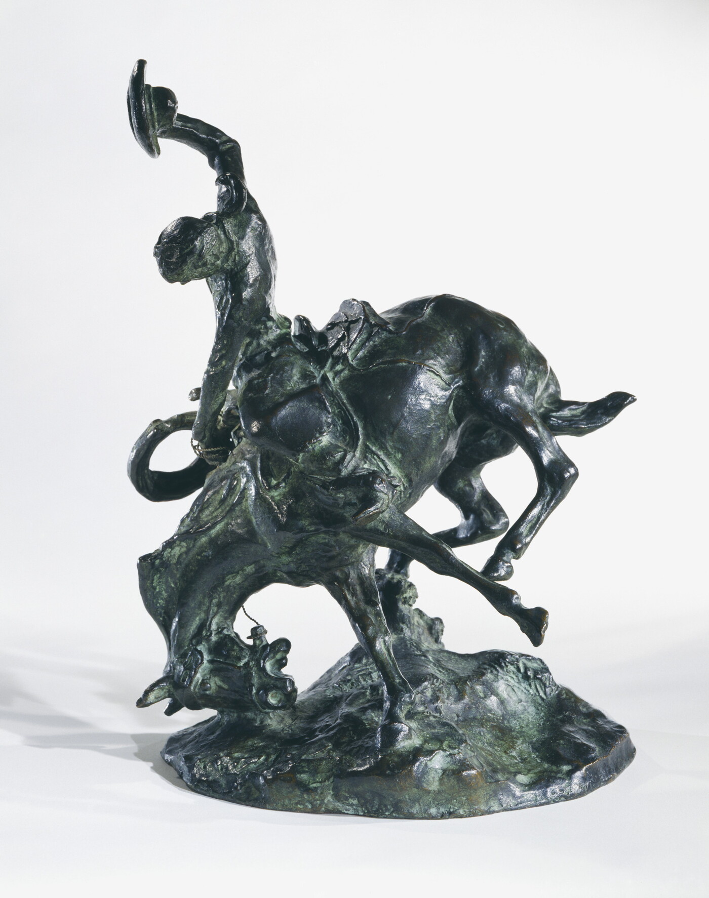 A bronze sculpture of a cowboy trying to ride a bucking horse.