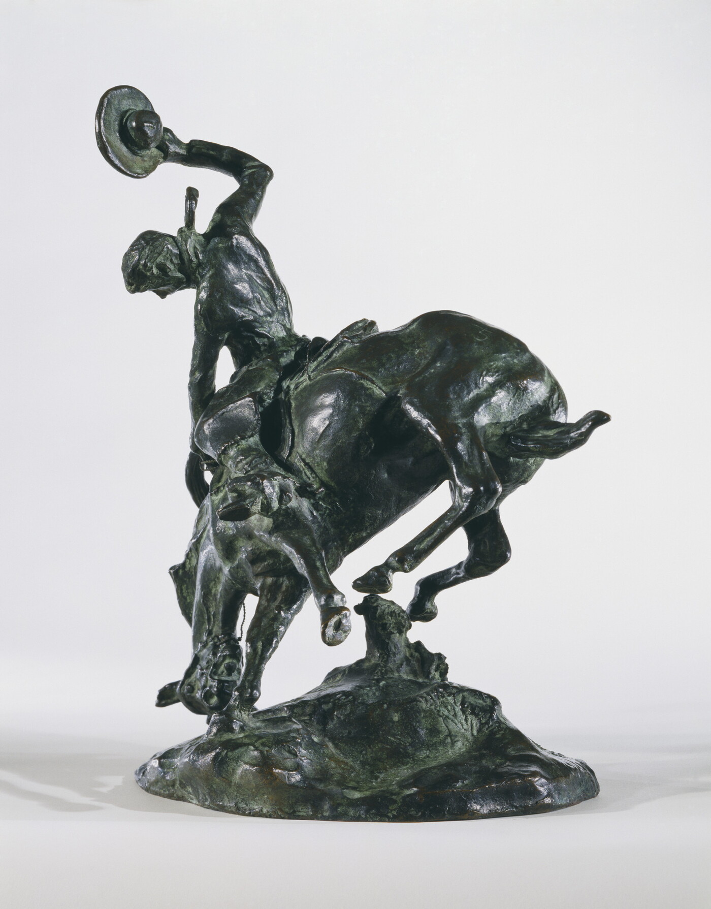 A bronze sculpture of a cowboy trying to ride a bucking horse.