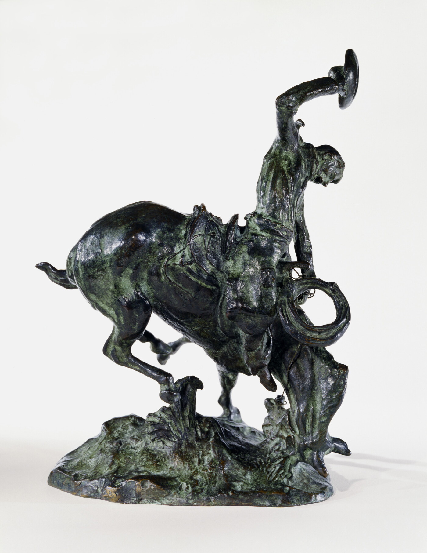 A bronze sculpture of a cowboy trying to ride a bucking horse.