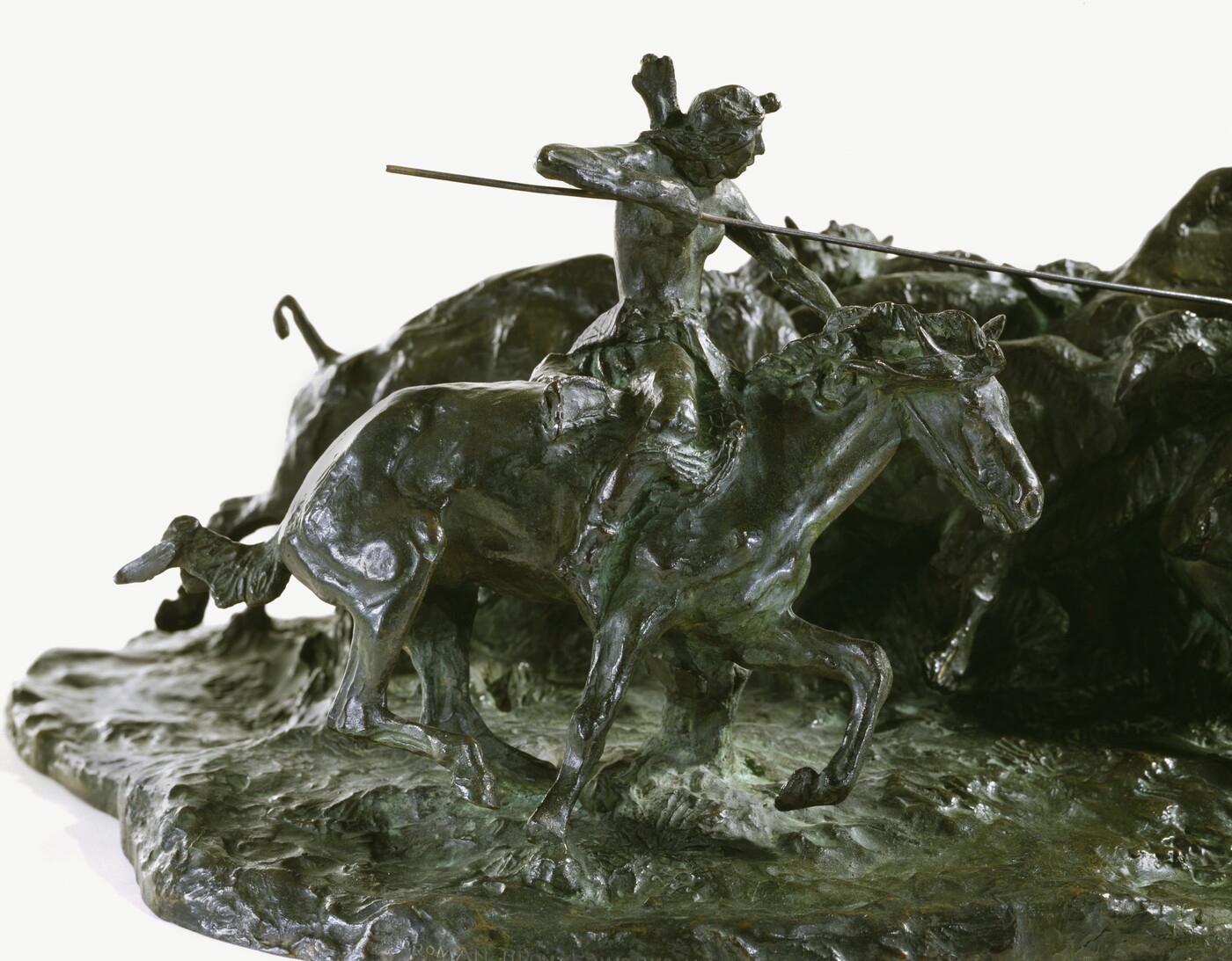 A detail of a bronze sculpture of two Native men, one with a spear and the other with a bow, on horseback circling a group of bison.