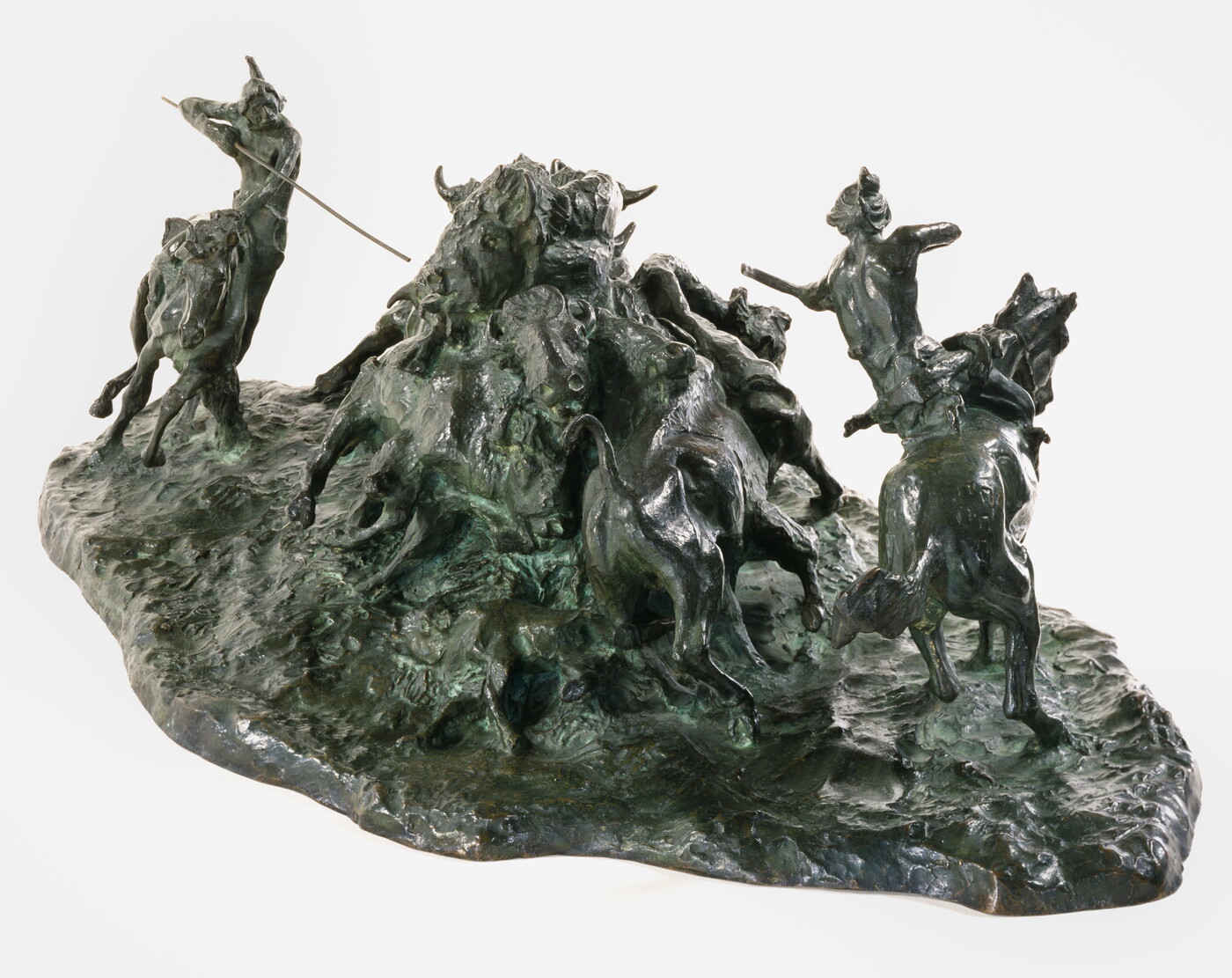 A bronze sculpture of two Native men, one with a spear and the other with a bow, on horseback circling a group of bison.