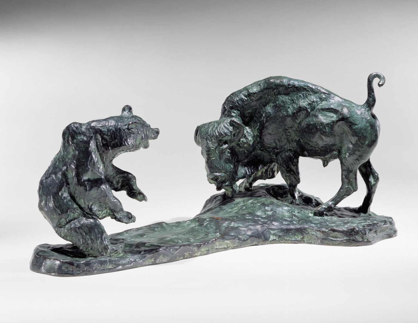A bronze sculpture of a bison and a bear facing off.
