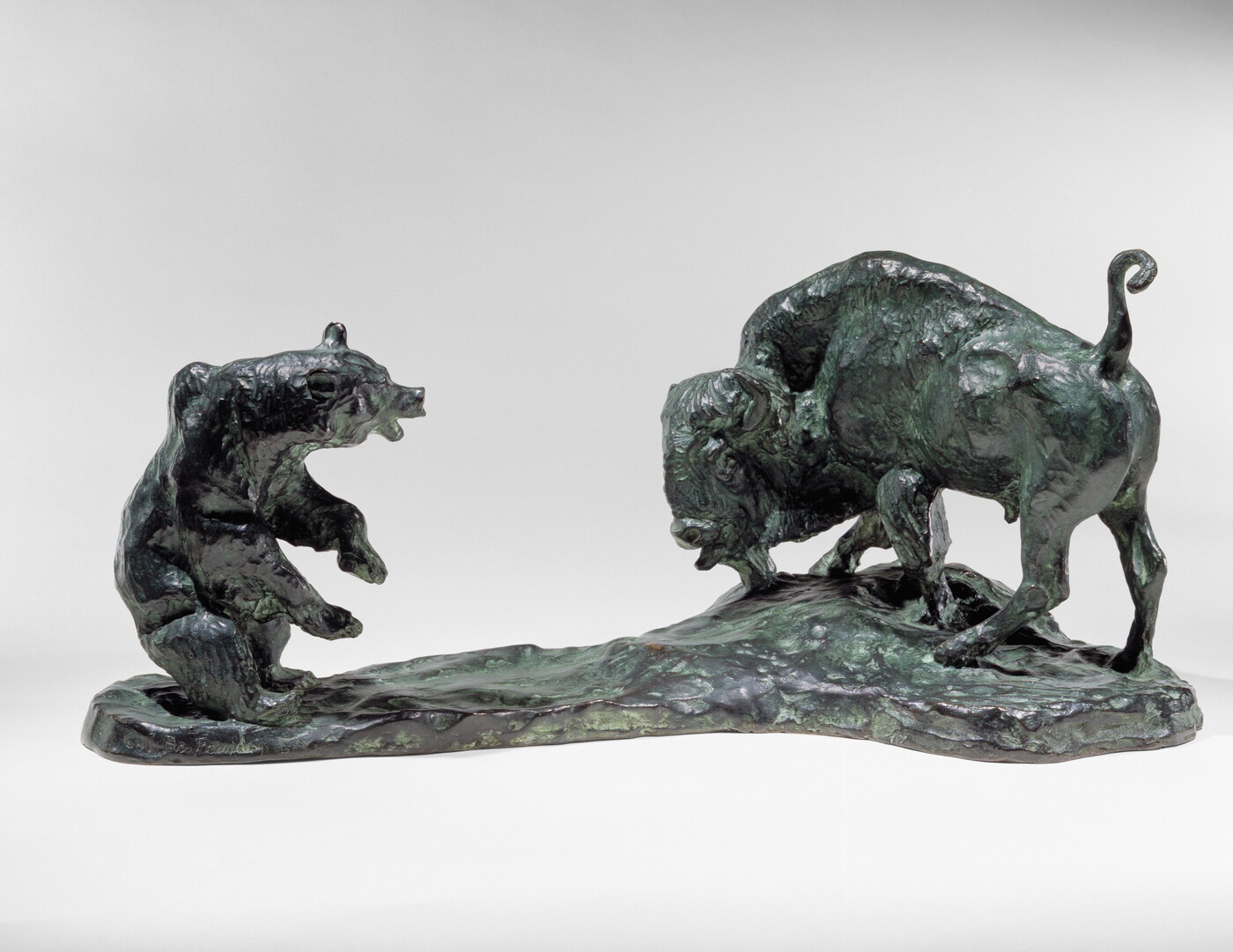 A bronze sculpture of a bison and a bear facing off.
