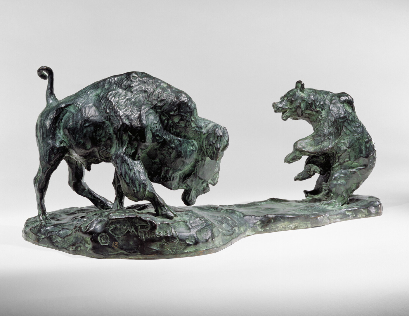 A bronze sculpture of a bison and a bear facing off.