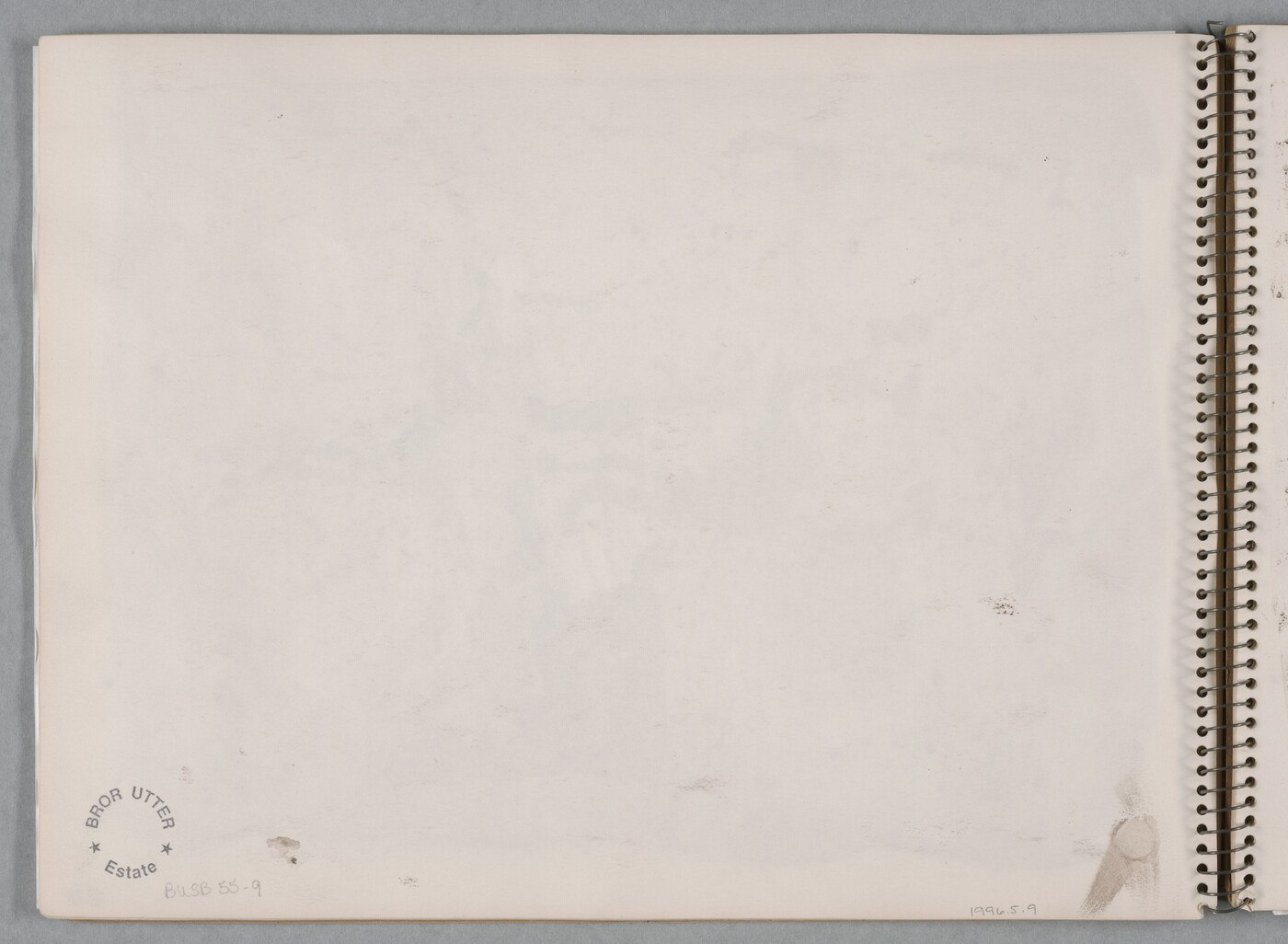 An abstract watercolor of sepia-toned splatters on a page of a bound sketchbook.