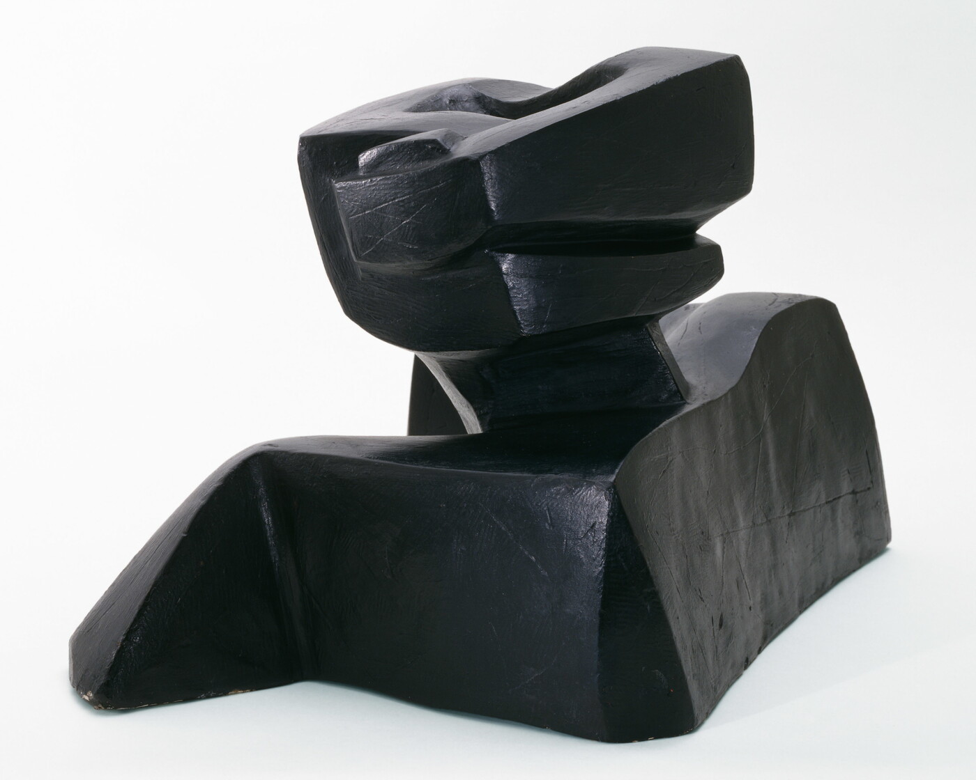 An abstract, black sculpture resembling a figure&#039;s head and shoulders.
