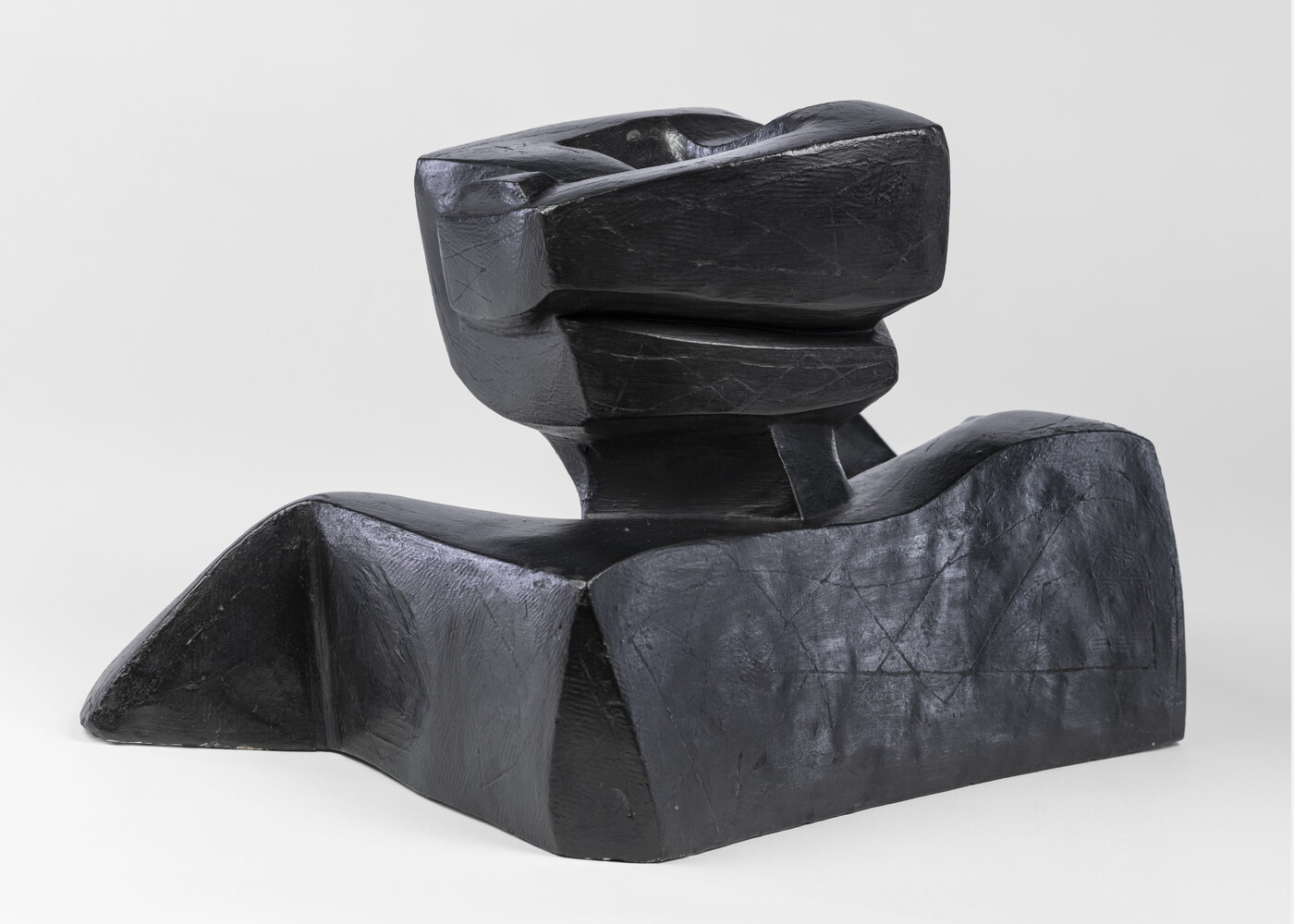 An abstract, black sculpture resembling a figure's head and shoulders.