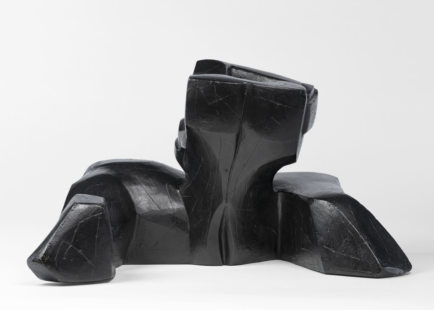 An abstract, black sculpture resembling a figure&#039;s head and shoulders.