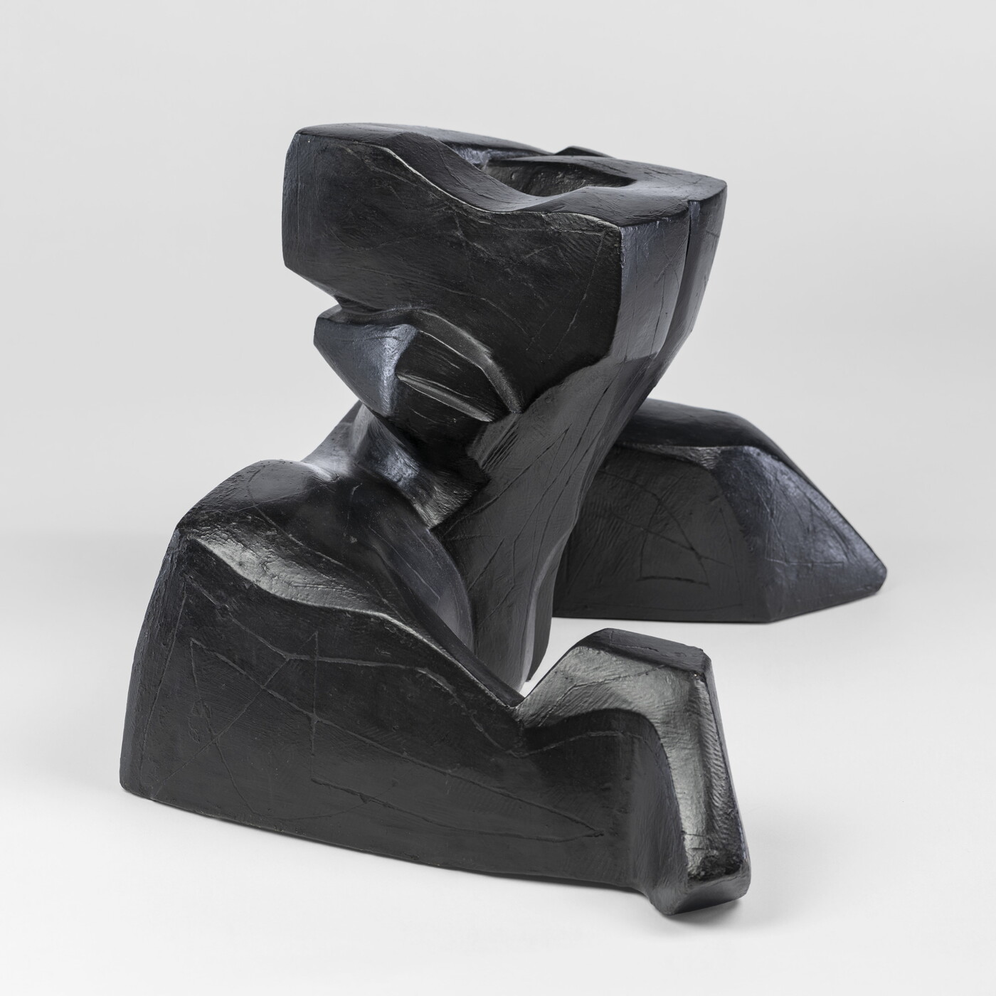 An abstract, black sculpture resembling a figure&#039;s head and shoulders.