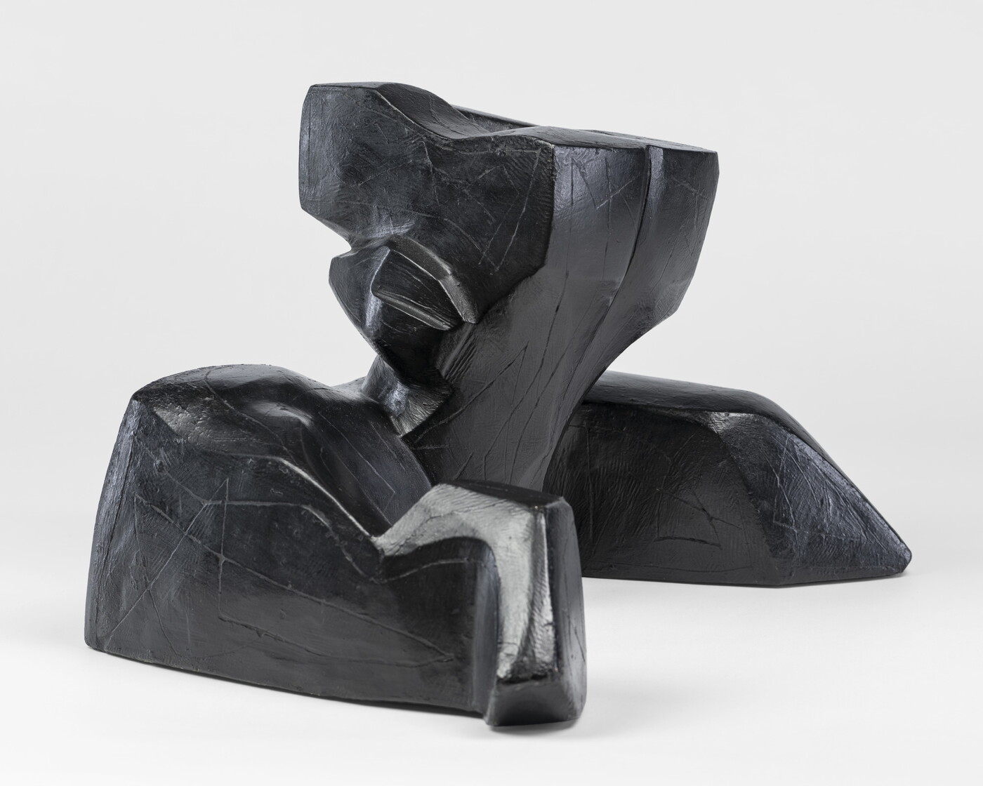 An abstract, black sculpture resembling a figure&#039;s head and shoulders.