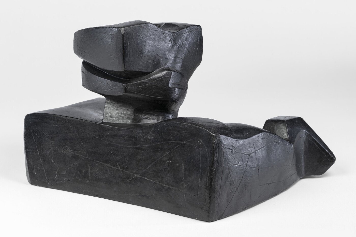 An abstract, black sculpture resembling a figure&#039;s head and shoulders.