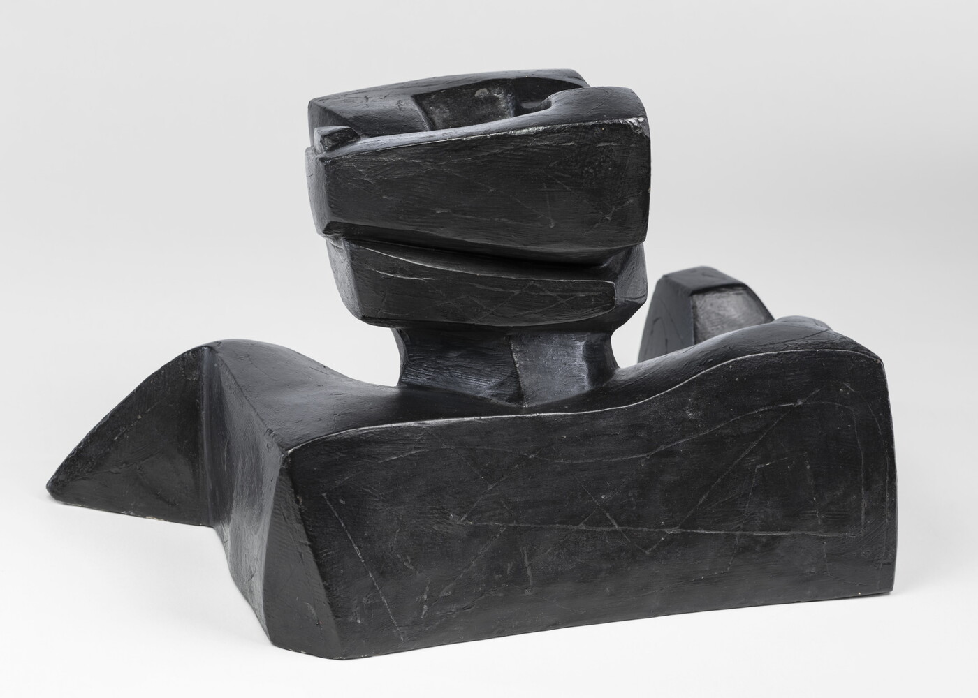 An abstract, black sculpture resembling a figure&#039;s head and shoulders.