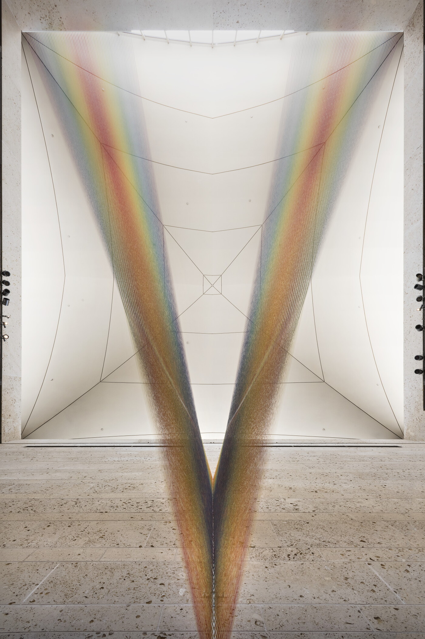 A large installation of multicolored sewing thread that stretches from one wall to the ceiling in the Carter&#039;s Atrium and looks like a rainbow.