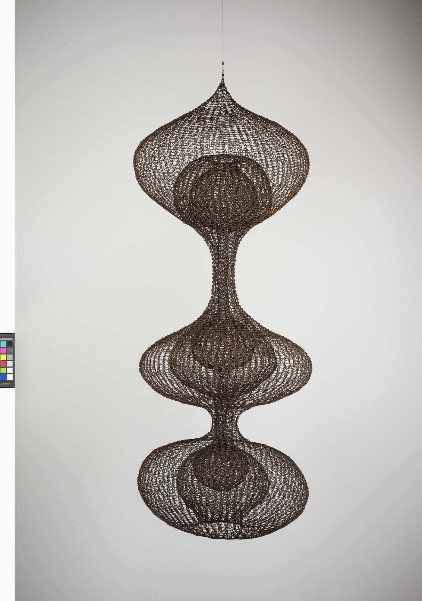 A hanging sculpture made of woven wire thread that creates three orb like shapes with smaller orbs nested inside each.