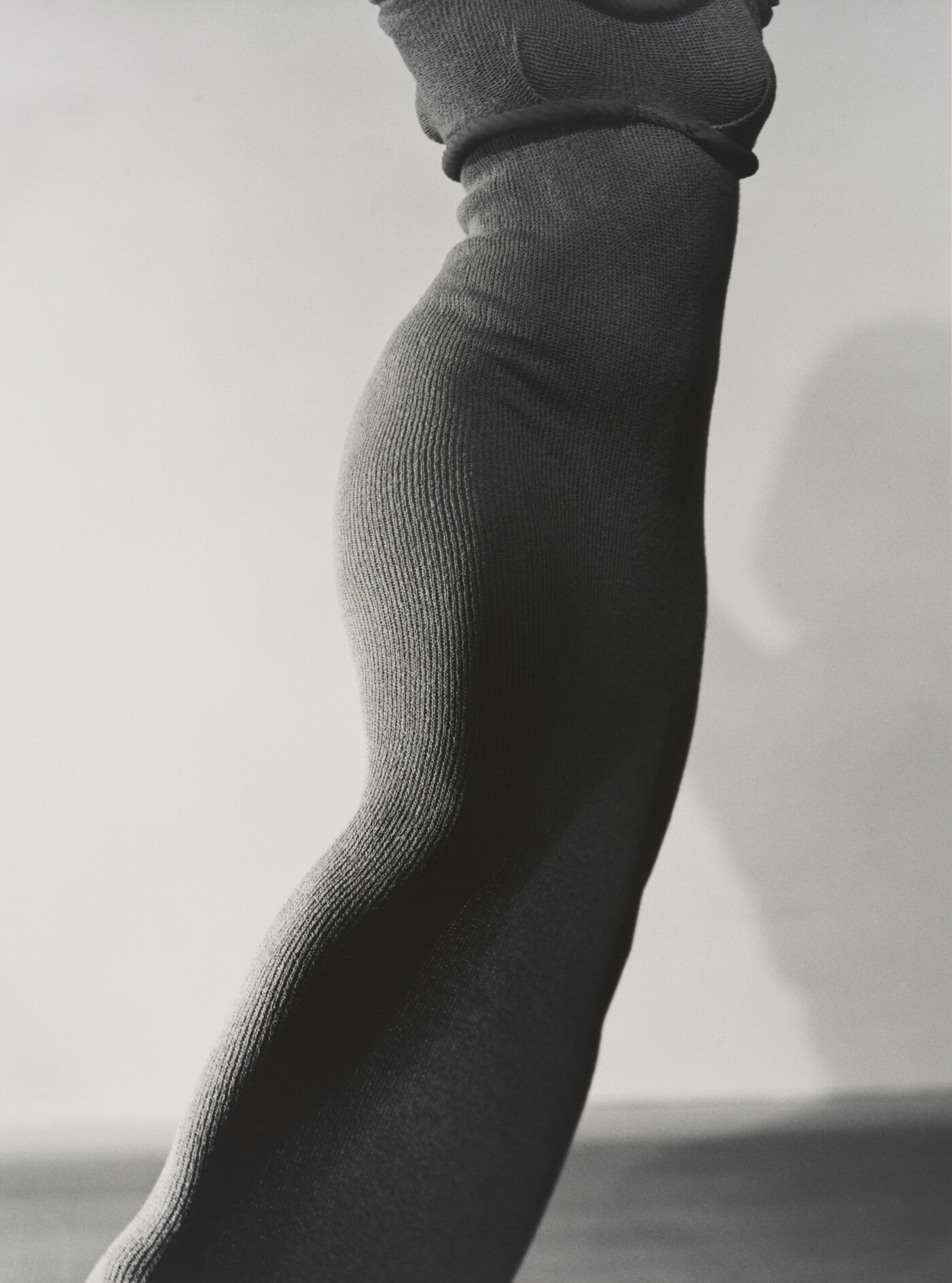 A black-and-white photograph of a slim, feminine torso wearing a form-fitting, knit dress.