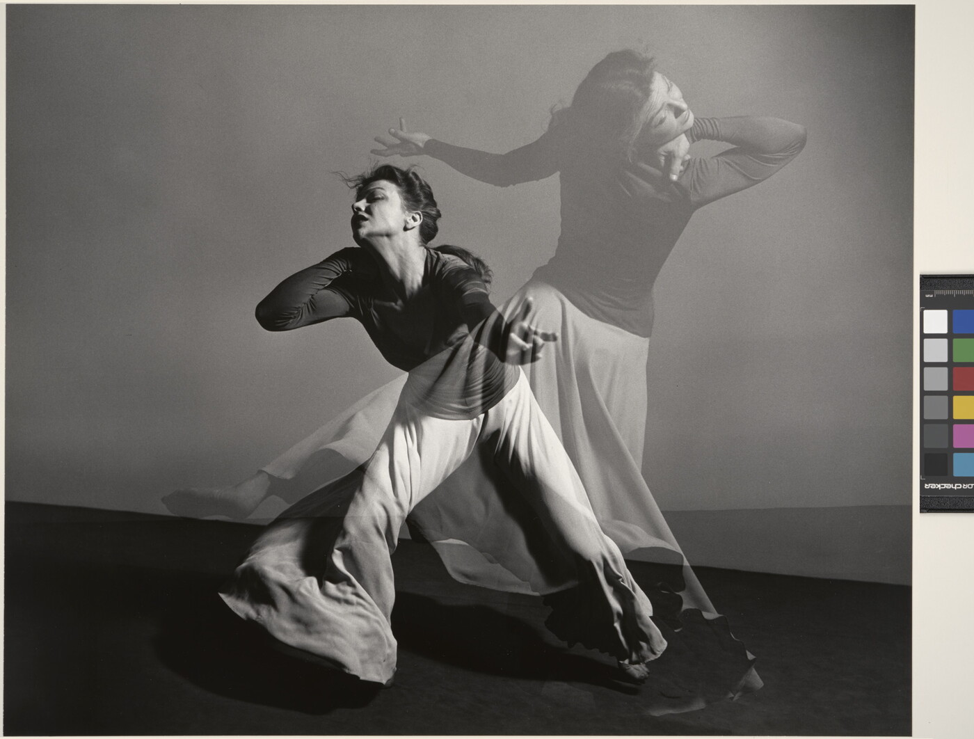 A double-exposed, black-and-white photograph of a female figure dancing dramatically.