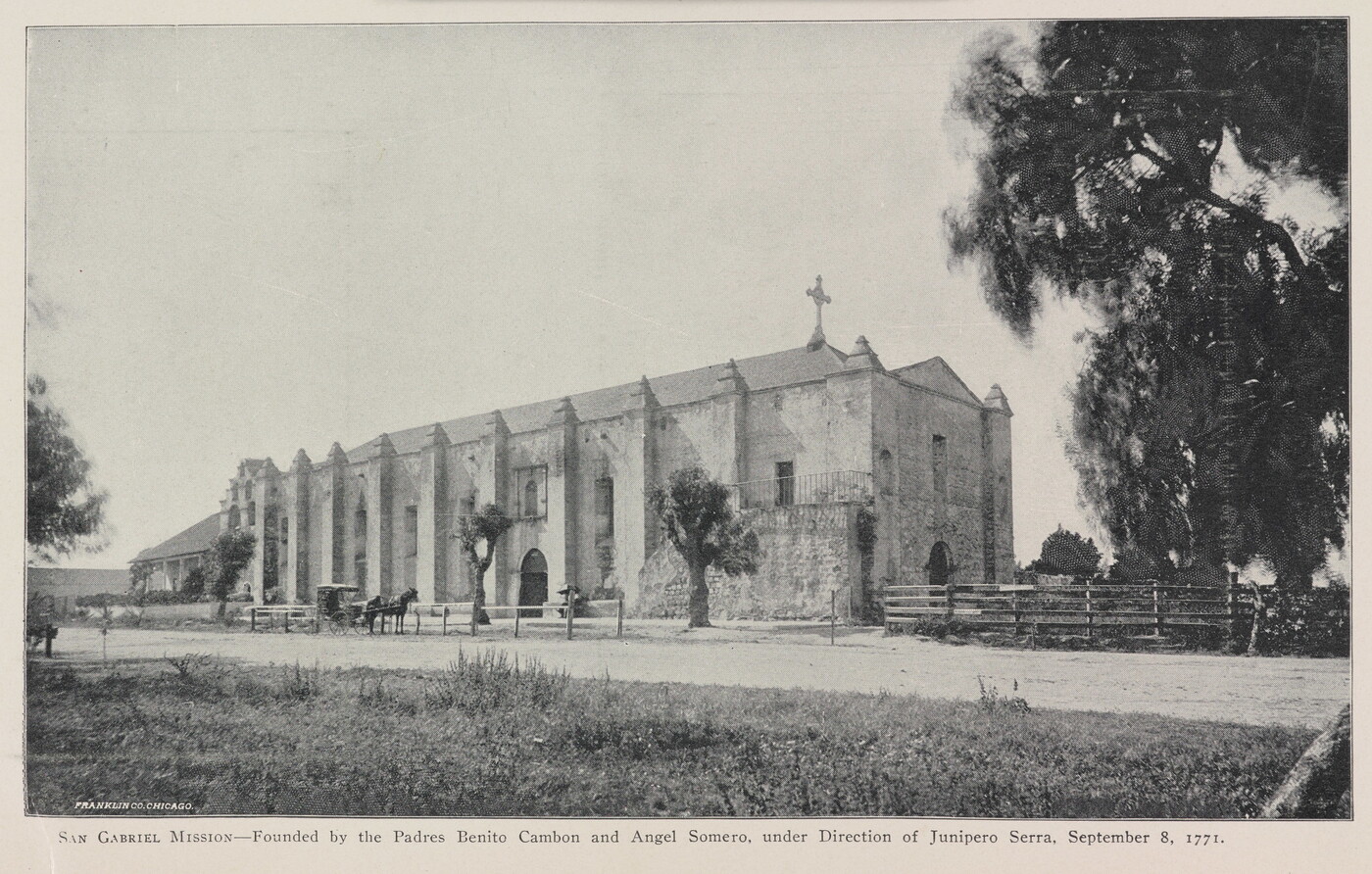 A black-and-white photograph of a mission church by a dirt road.