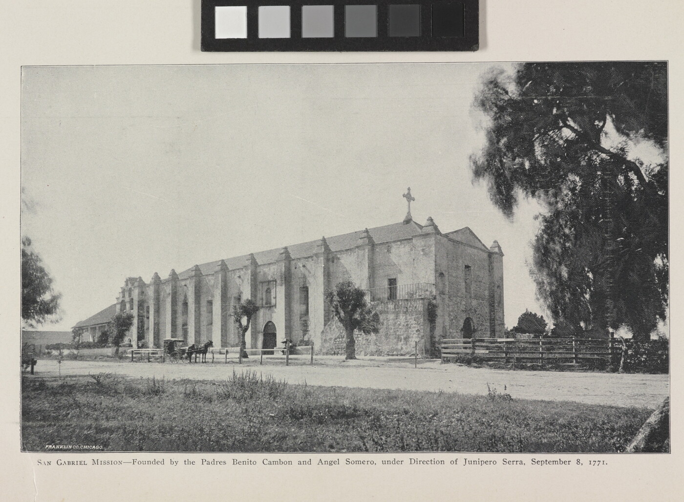 A black-and-white photograph of a mission church by a dirt road.