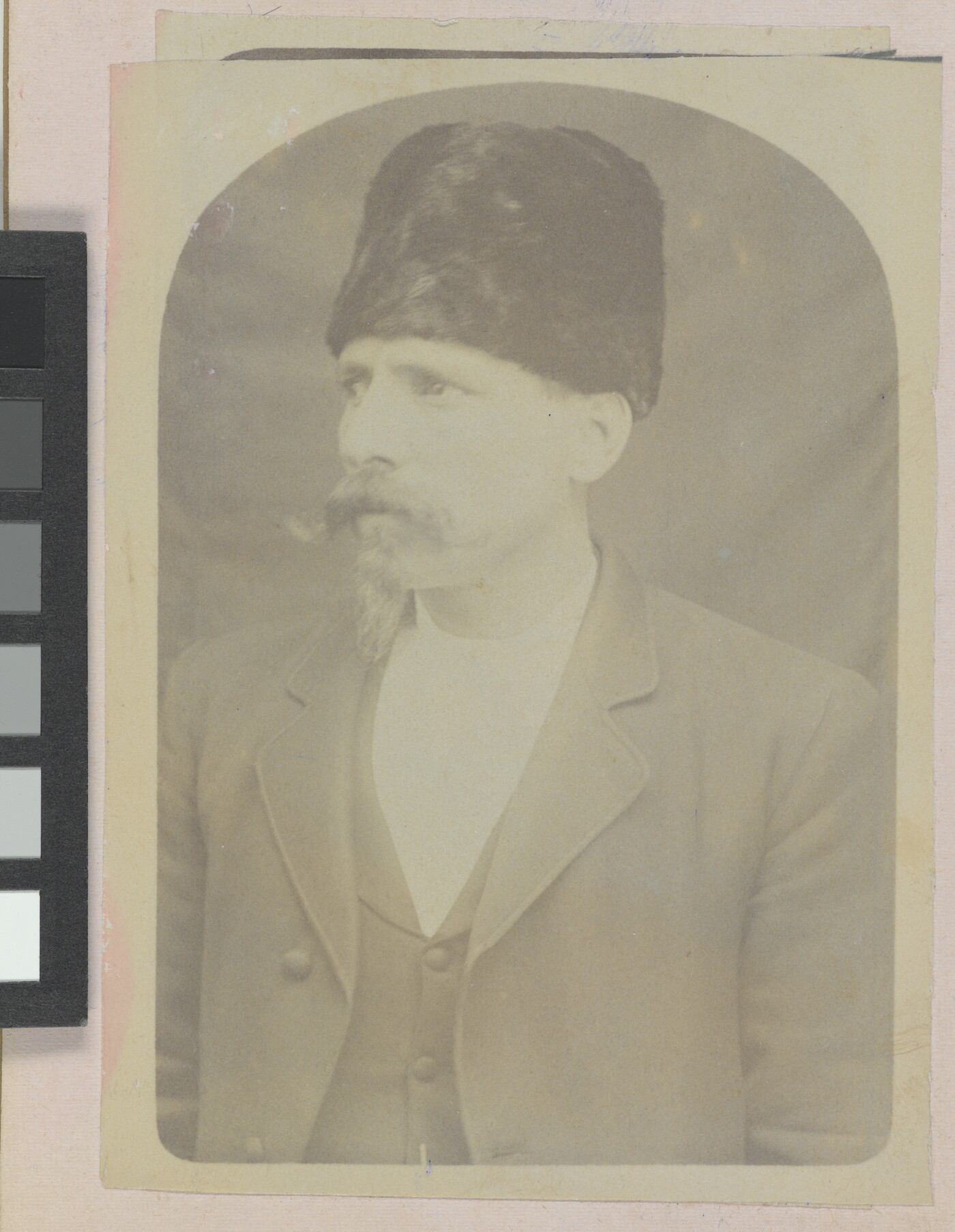 A faded sepia-toned portrait of a White man with a handlebar moustache wearing a fur Cossack-stye hat and a three-piece suit.