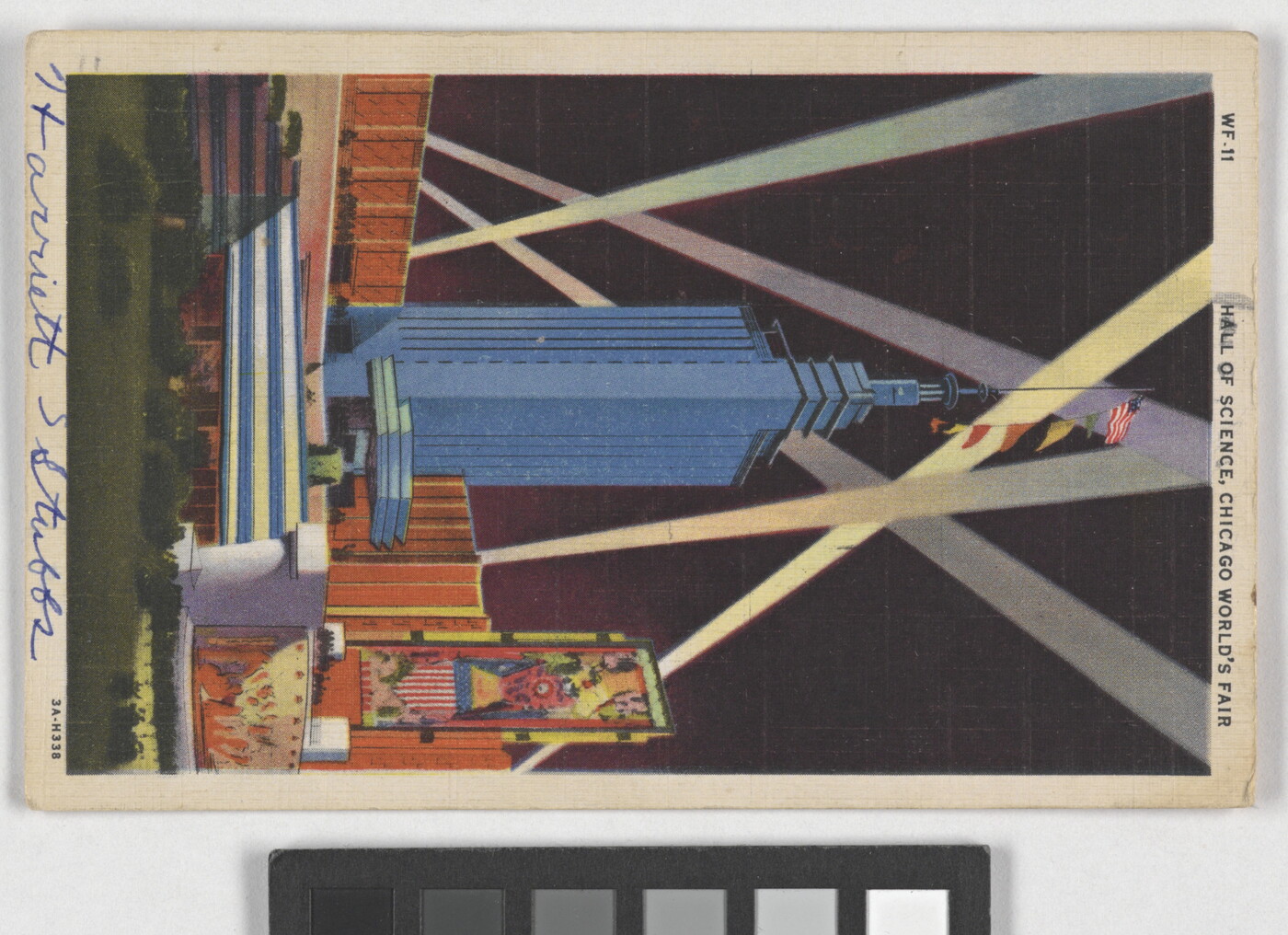 A color postcard of a tall, modern skyscraper illuminated by beams of light.
