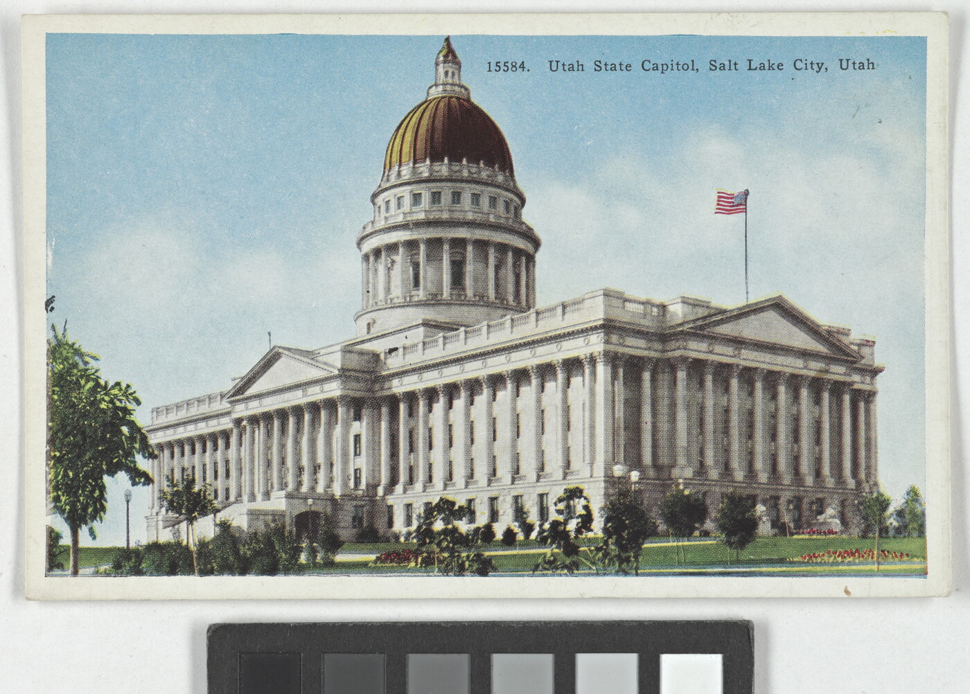 A color postcard of a gold domed government building with many columns.