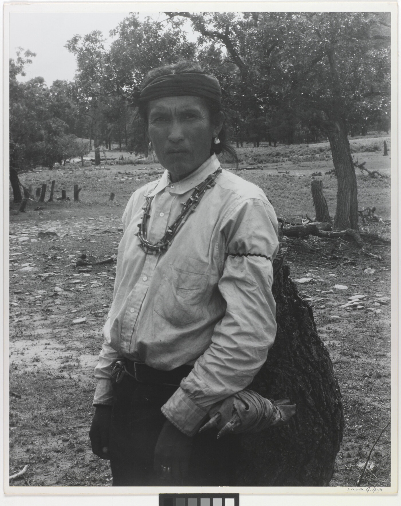 A black-and-white photograph of an Indigenous man carrying a large bag.