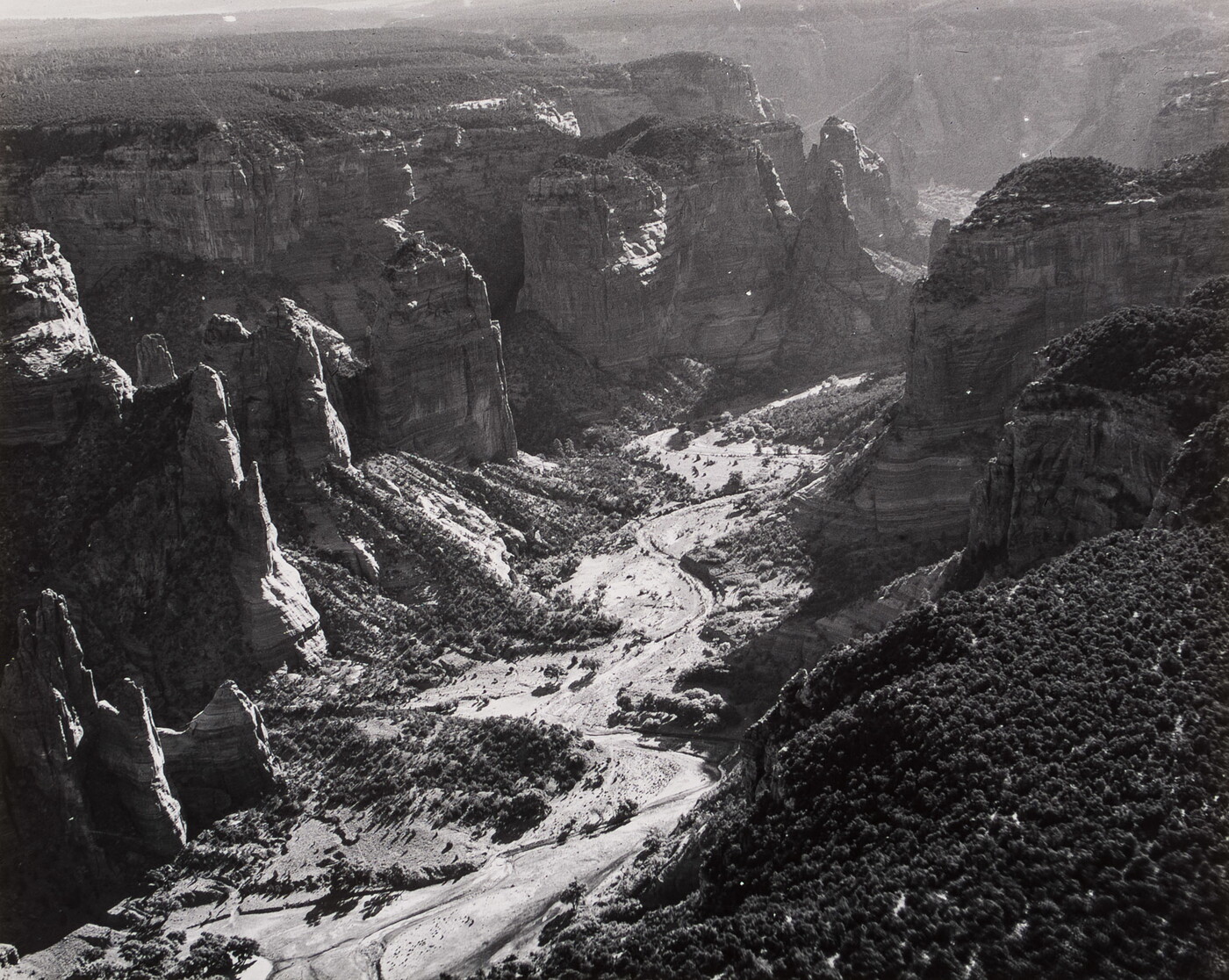 A black-and-white photograph of a landscape with two sides of steep and rocky cliffs and a dry valley between them.