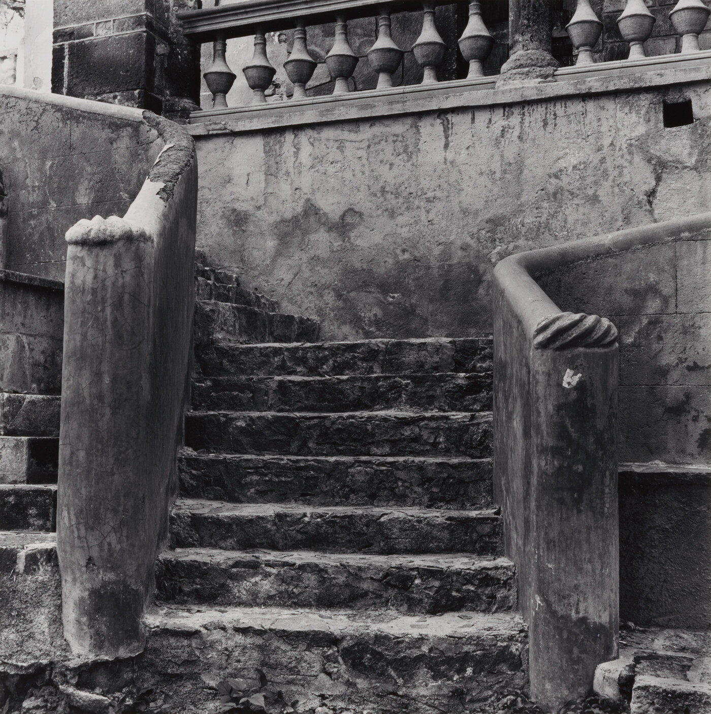 A black-and-white photograph of a decorative stone staircase that is starting to crumble.