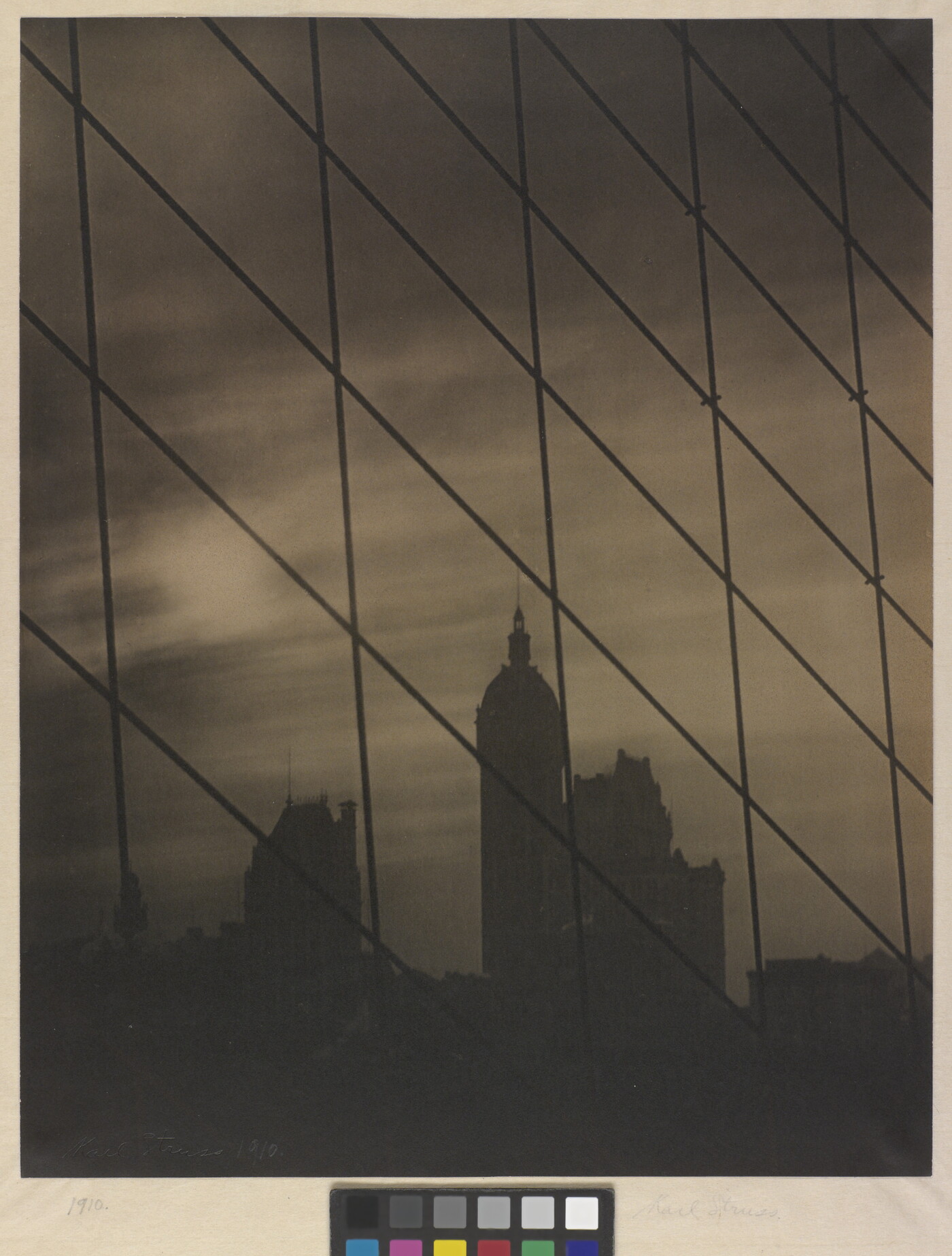 A sepia-toned photograph of a patterned grid of cables in front of a dark city skyline.