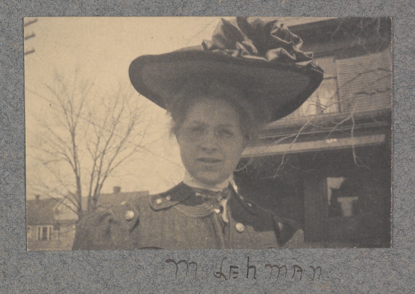 A black-and-white photograph of a White woman from the shoulders up, wearing a large brimmed hat with ruffles on top.