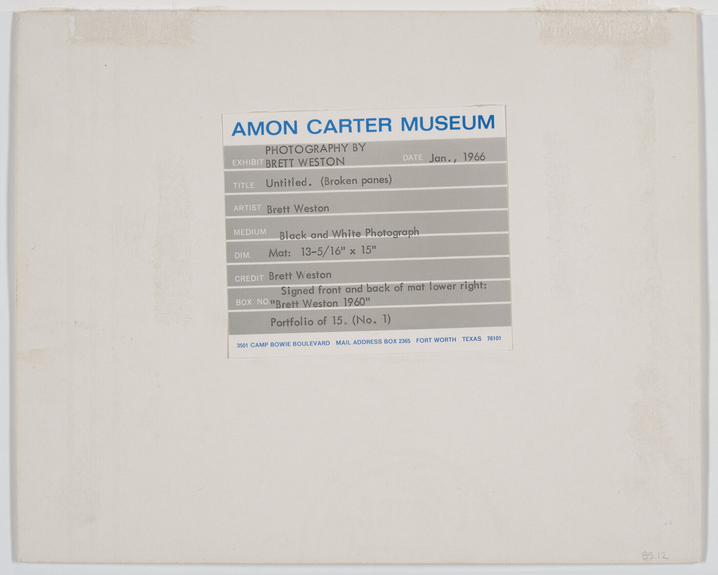 A black-and-white photograph of broken window panes in what looks like a factory building.