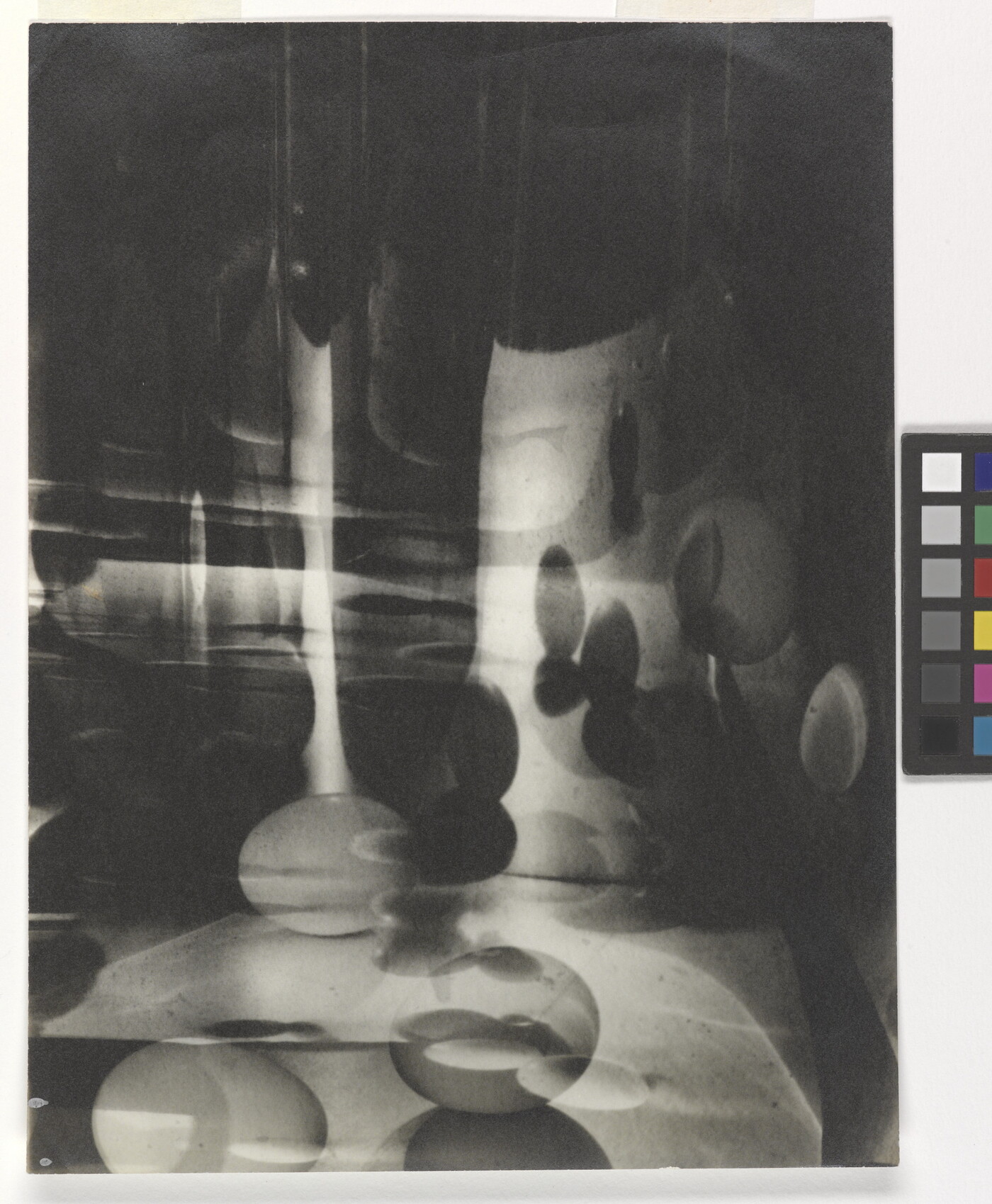 A black-and-white photograph of abstracted egg shapes layered and reflected on top of one another.