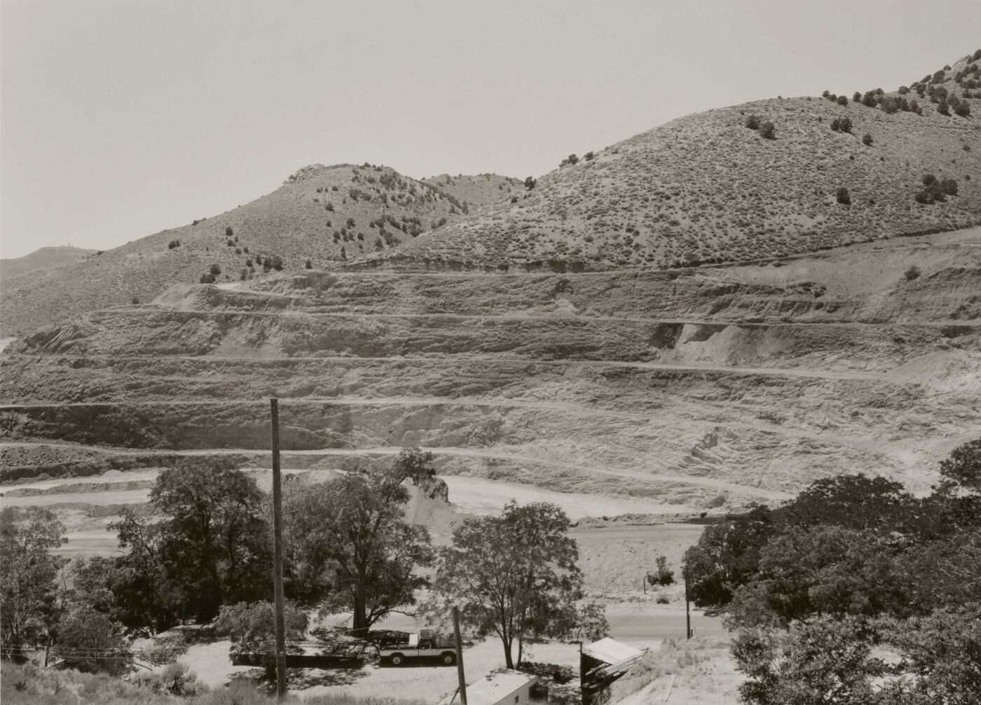 A black-and-white photograph of a mountainside that has been strip mined and the town below.