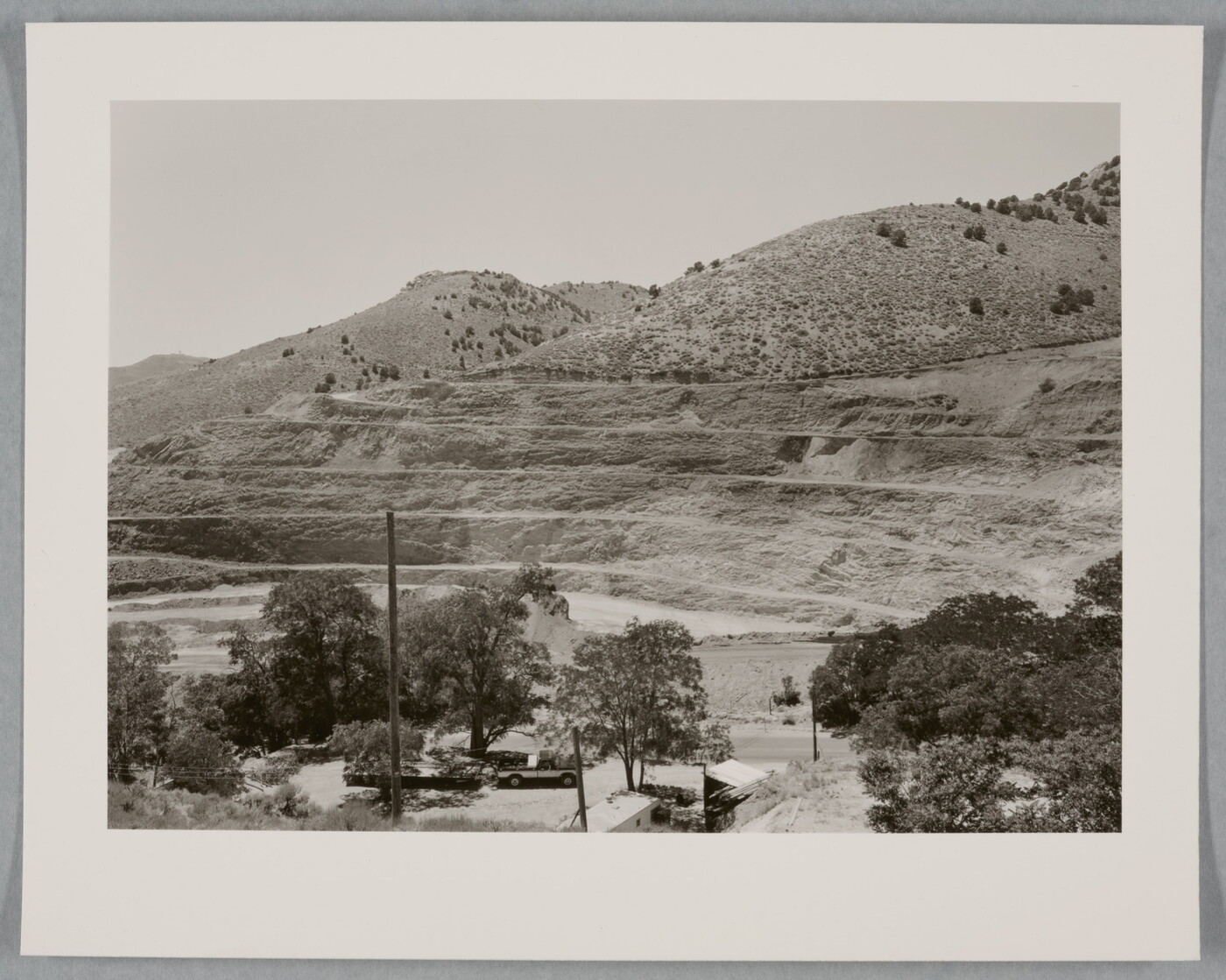 A black-and-white photograph of a mountainside that has been strip mined and the town below.