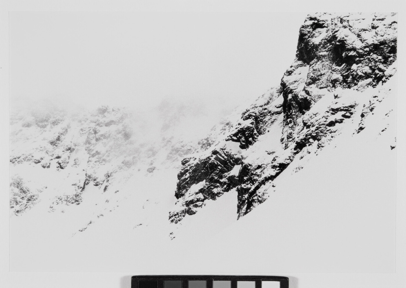 A black-and-white landscape photograph of a snowy mountain range.