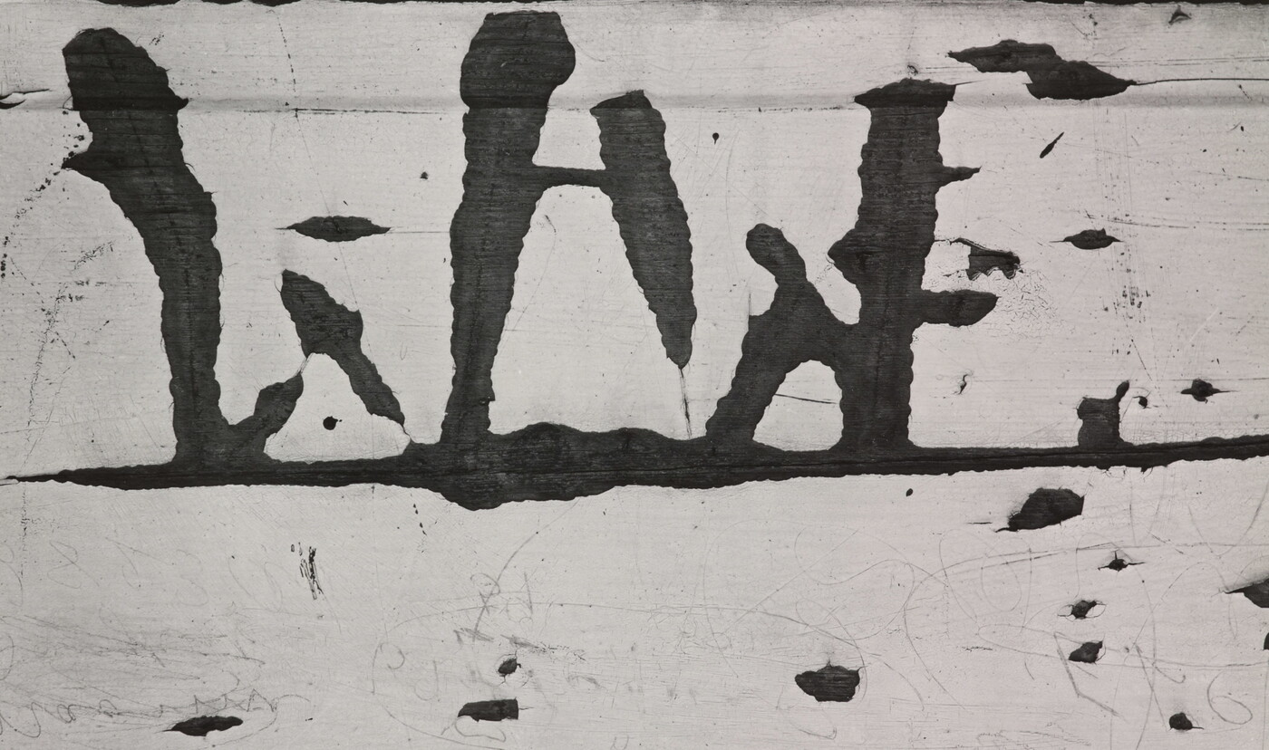 A black-and-white close-up photograph of white paint peeling off of wood.