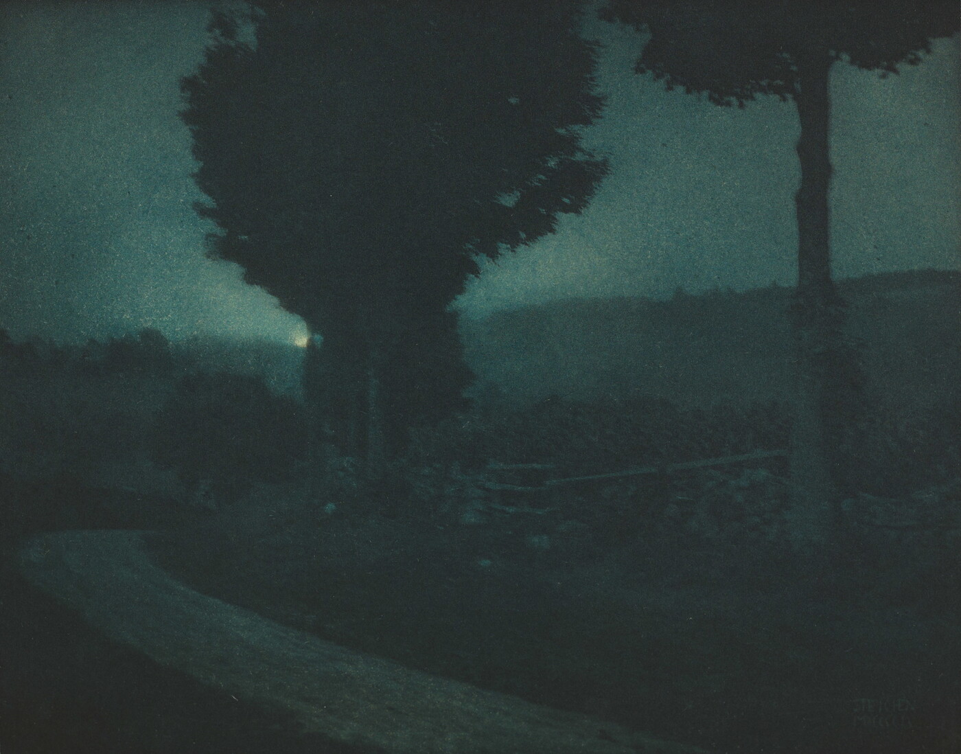 A black-and-white photograph of a tree-lined road in a dark, moonlit landscape.