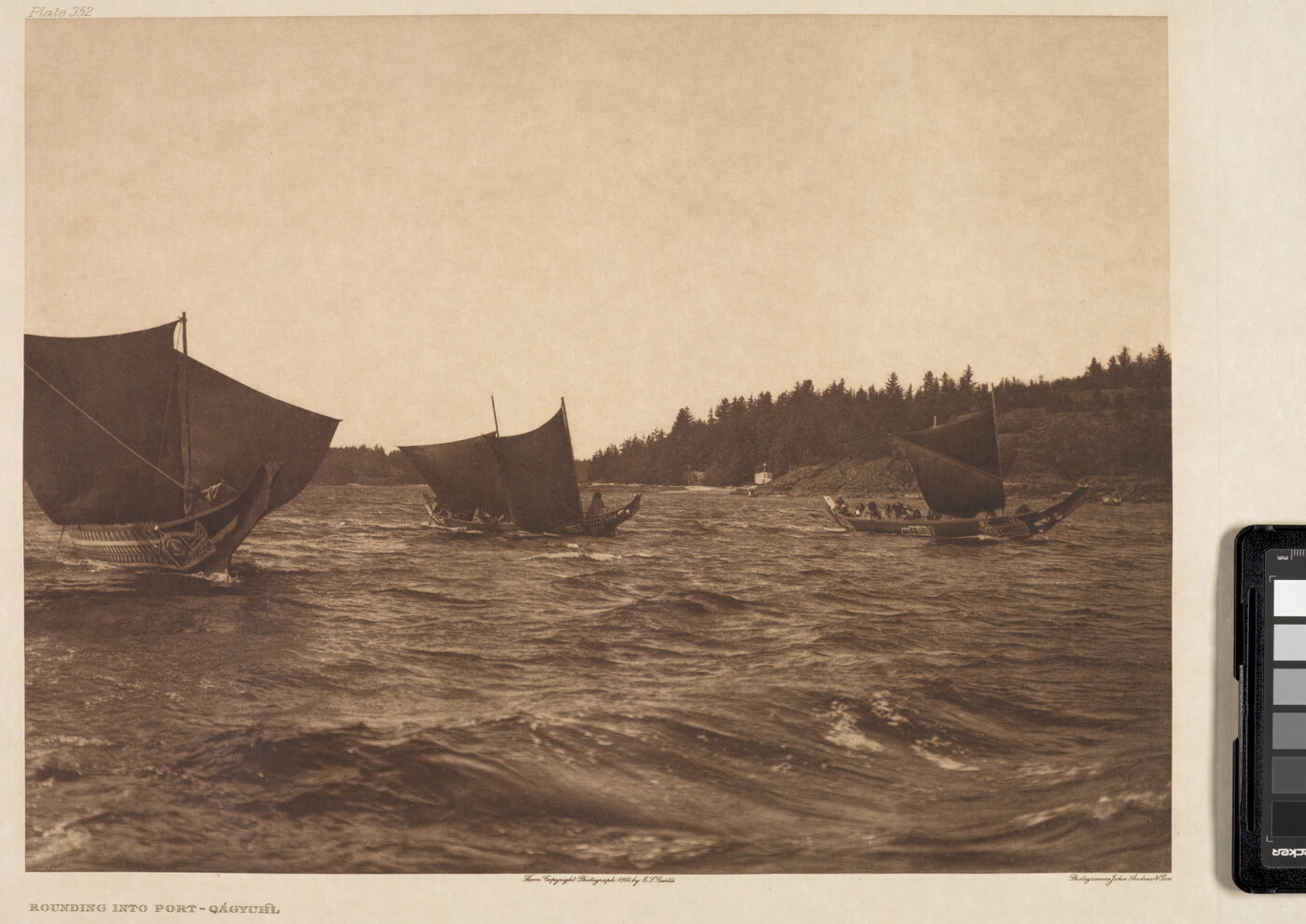 A sepia-toned photograph of three elaborately carved canoes with raised sails on choppy water.