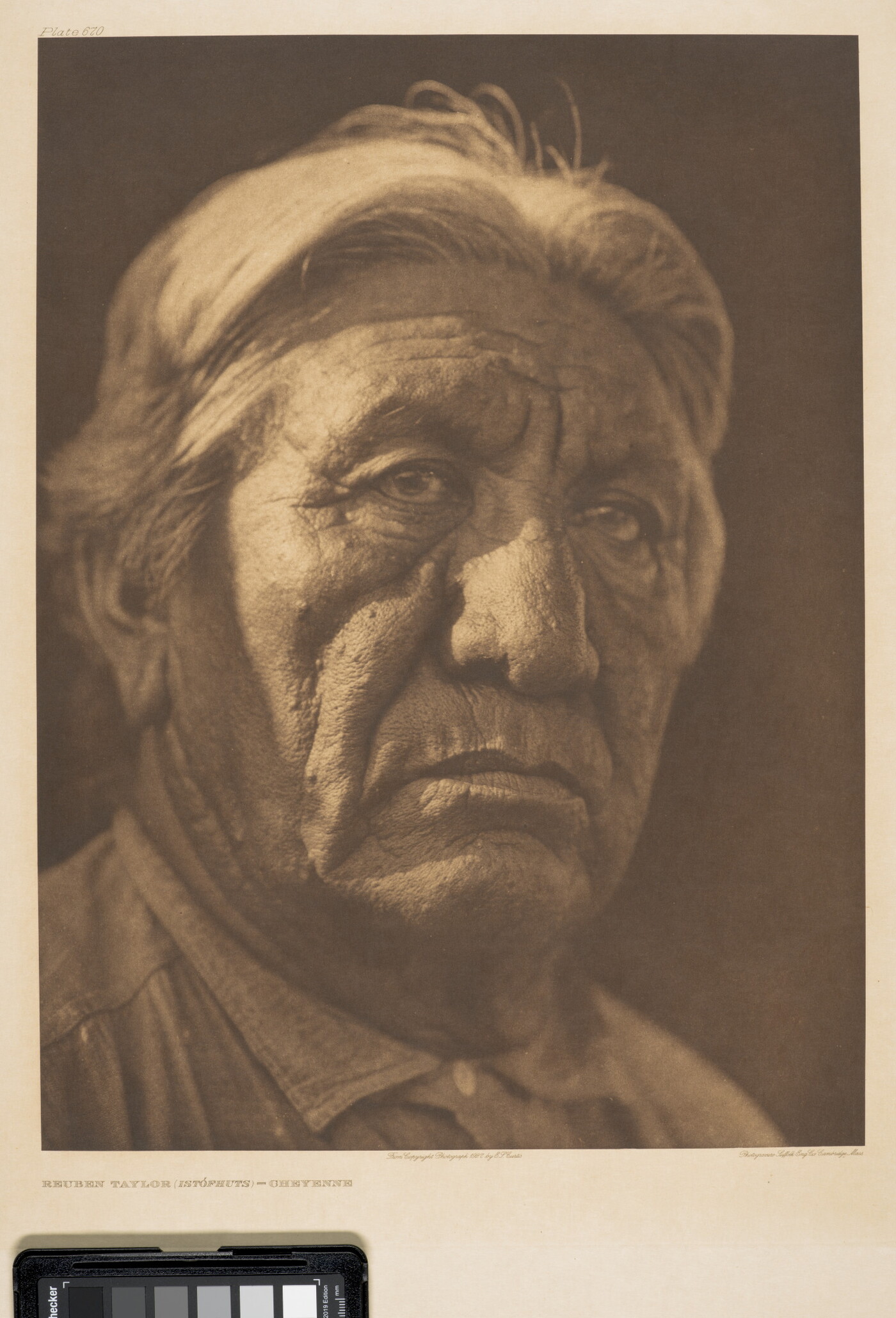 A sepia-toned portrait photograph of an older Indigenous man from the shoulders up wearing a collared shirt buttoned at the neck.