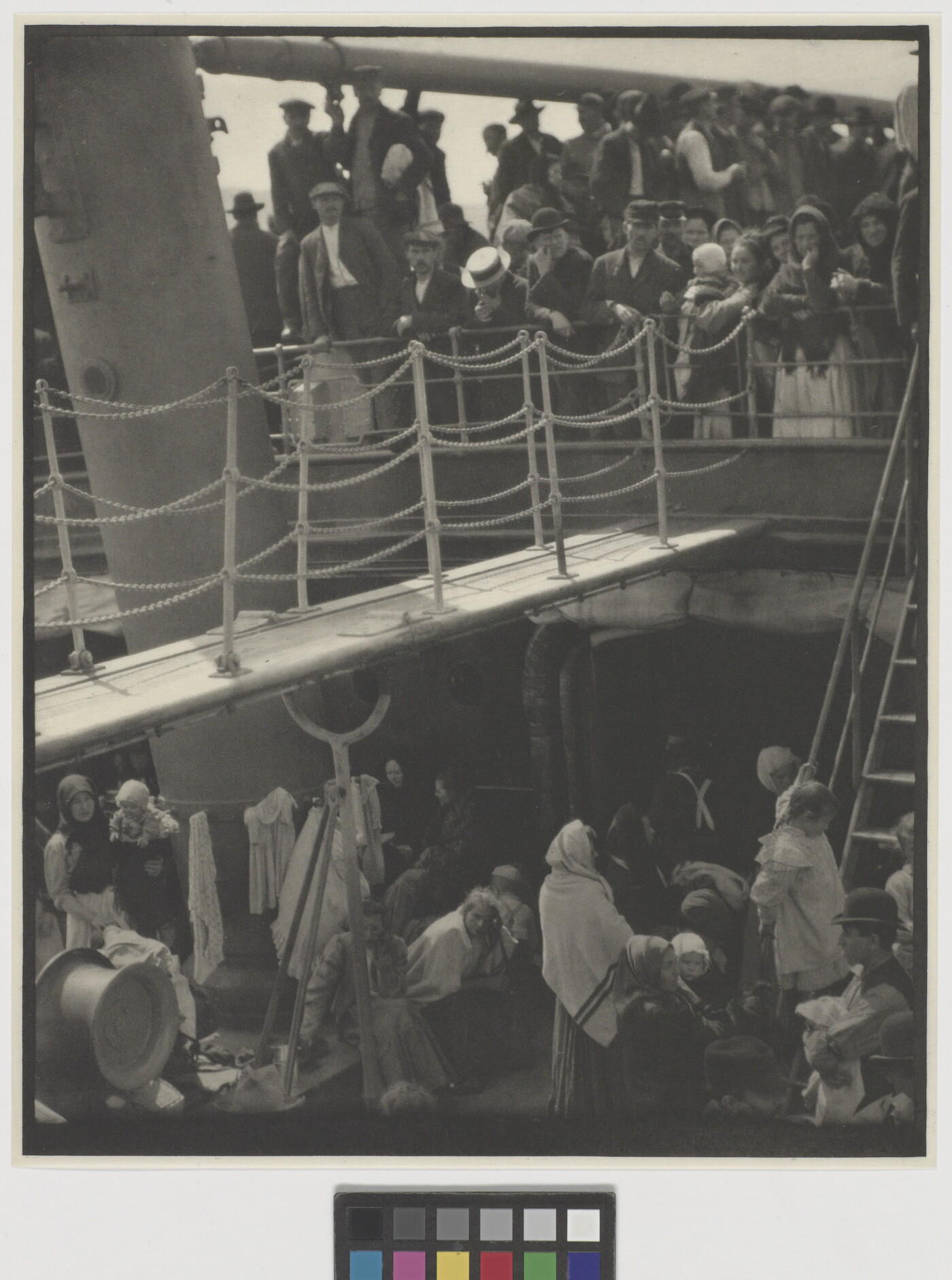 A black-and-white photograph of people outside on two decks of a crowded ship.