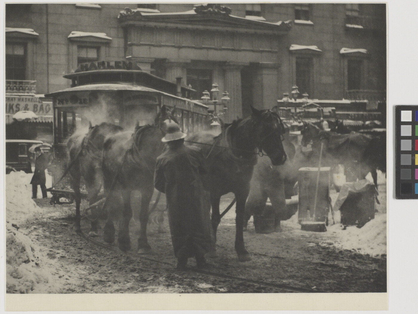 A black-and-white photograph of horses pulling a trolley on a busy street covered with slush and snow.