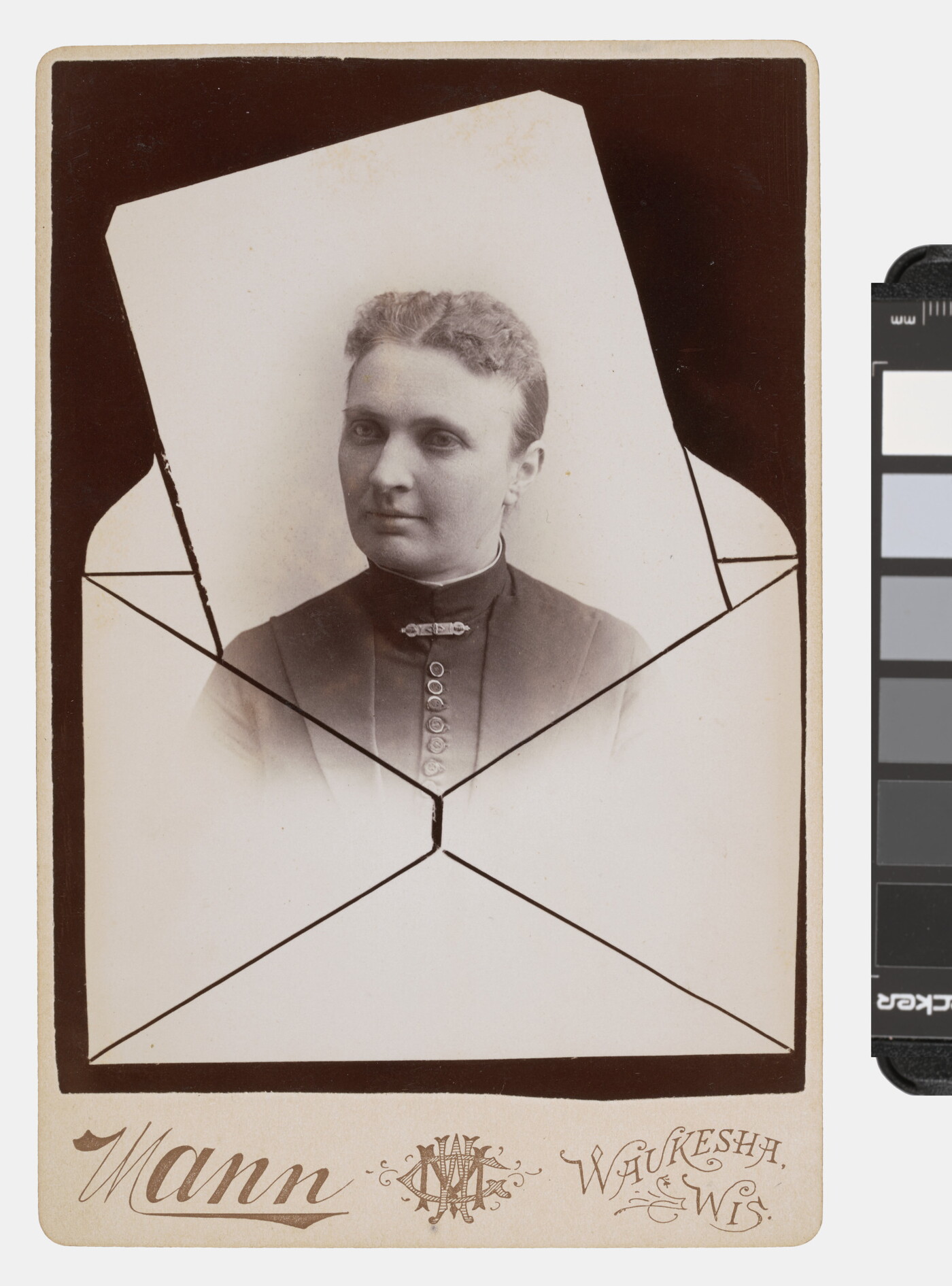 A sepia-toned studio photograph in which the bust of a White woman seems to be popping out of an envelope.
