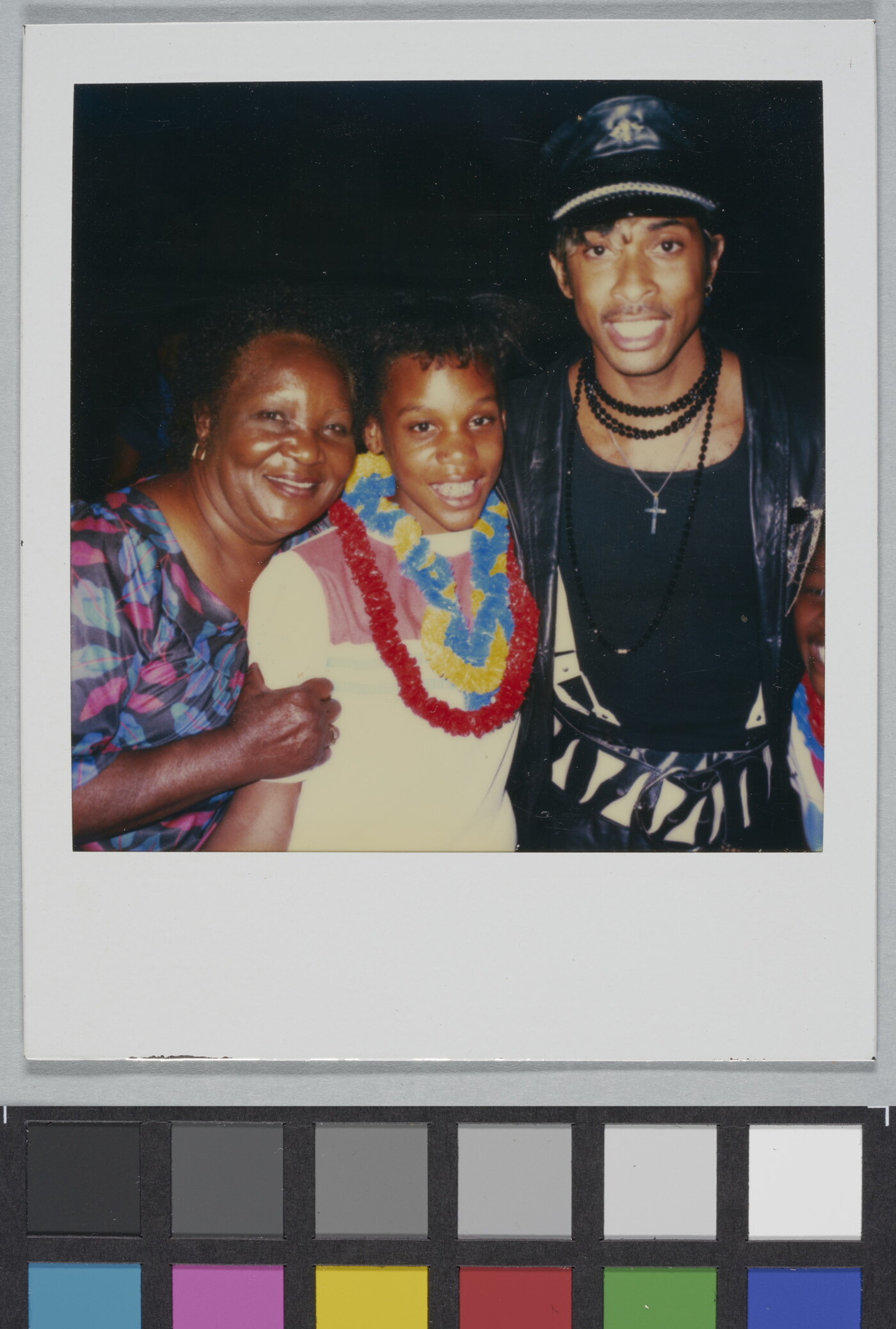 A color Polaroid photograph of a smiling Black woman, girl, and man posed standing together.