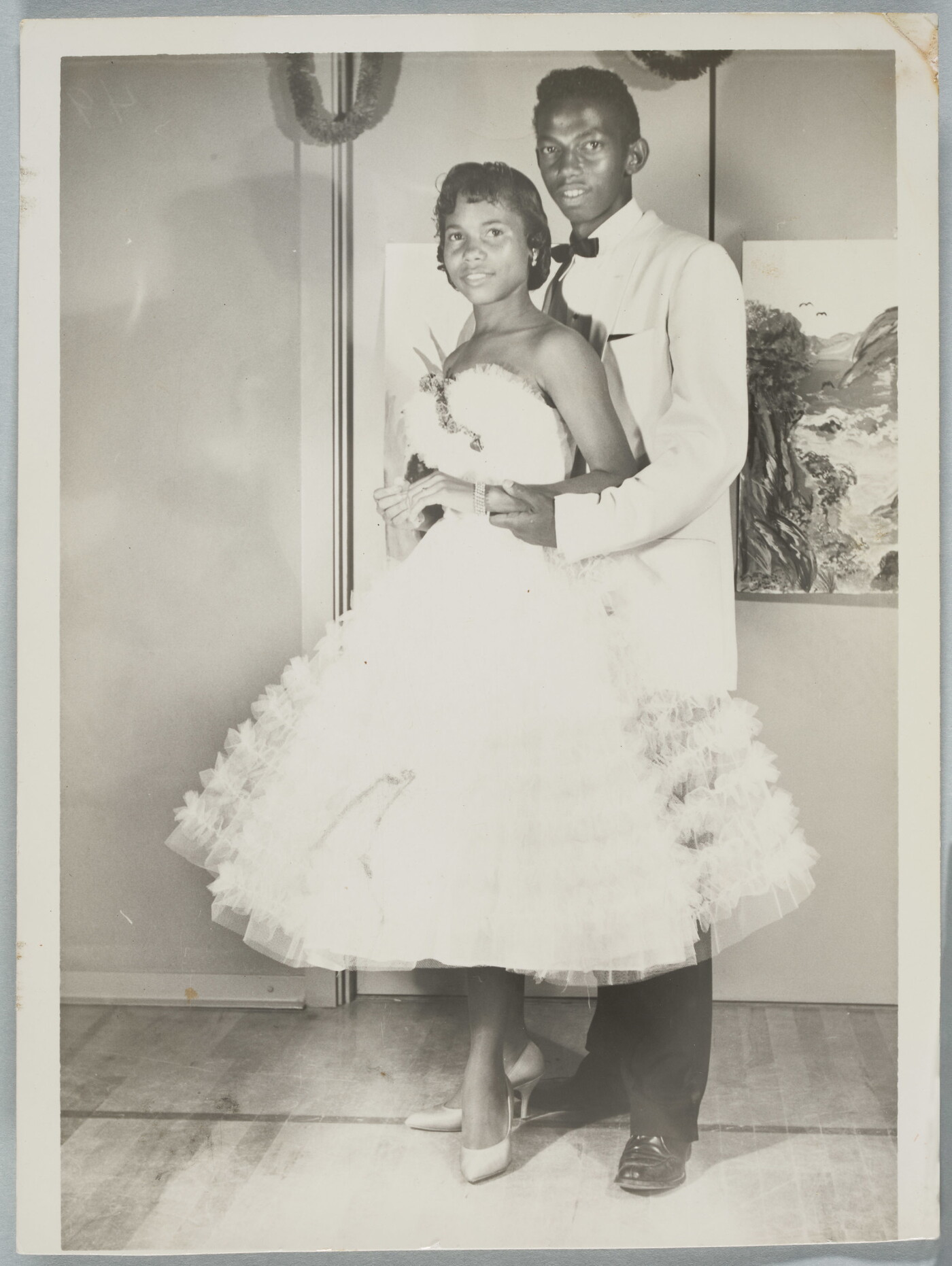 A black-and-white photograph of a Black couple in formal dress at a dance.